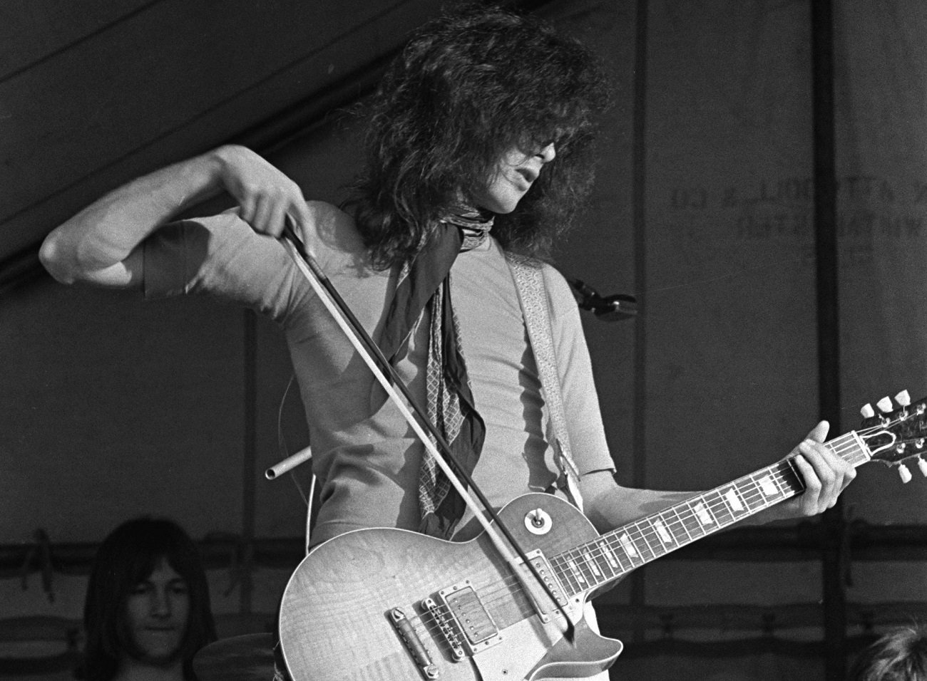 Jimmy Page playing his guitar on stage with a bow