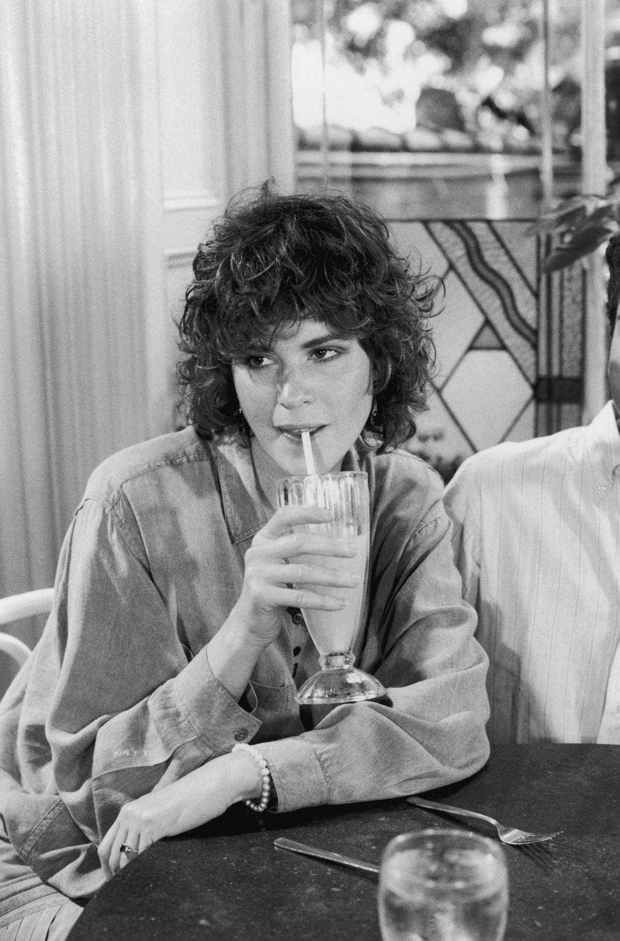 circa 1987:  American actor Ally Sheedy sips a large glass of orange juice at Serendipity restaurant in New York City