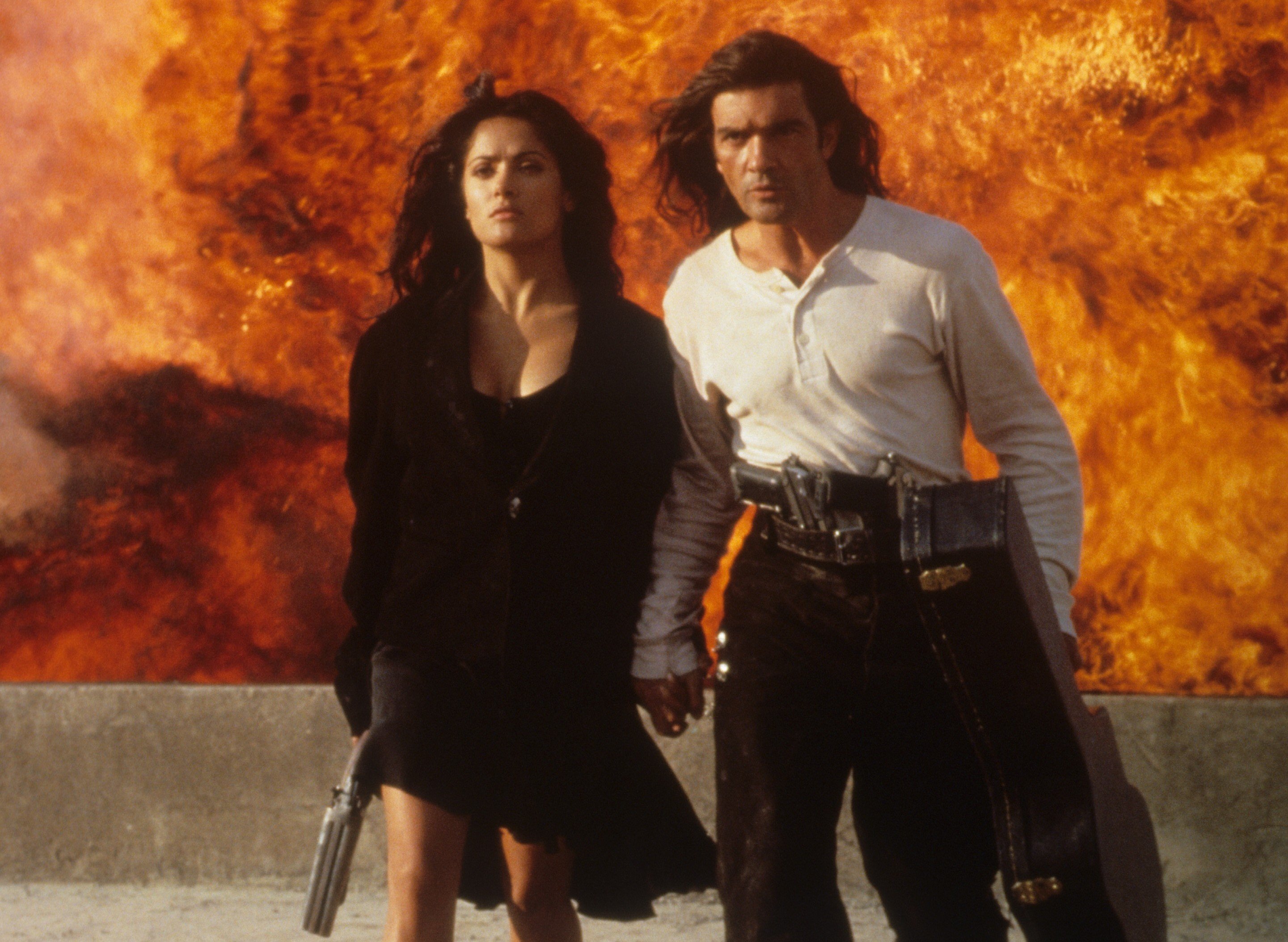 Antonio Banderas and Salma Hayek walking away from burning flames in scene from 'Desperado' 