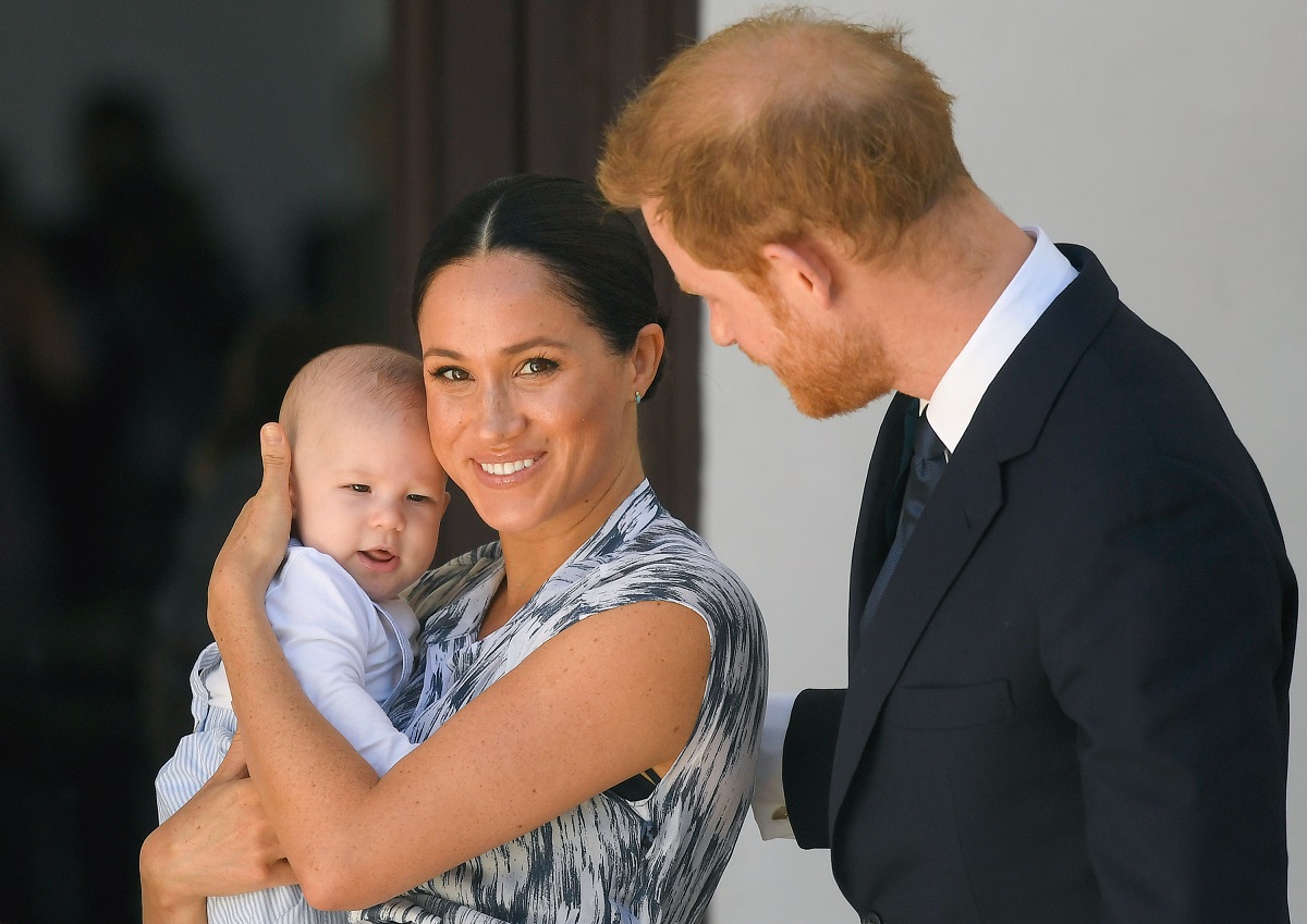 Prince Harry, Duke of Sussex, and Meghan, Duchess of Sussex, with baby Archie during their royal tour of South Africa in Cape Town; Meghan is smiling at the camera and holding Archie.