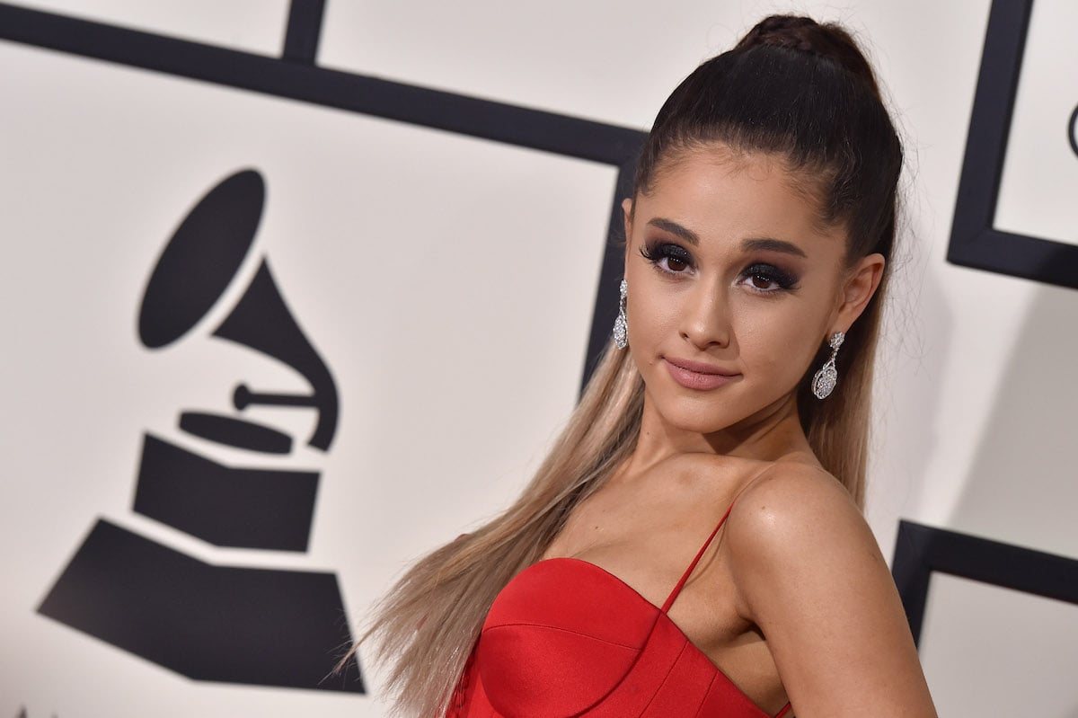 Ariana Grande posing facing the camera with a red dress and a high pony-tail