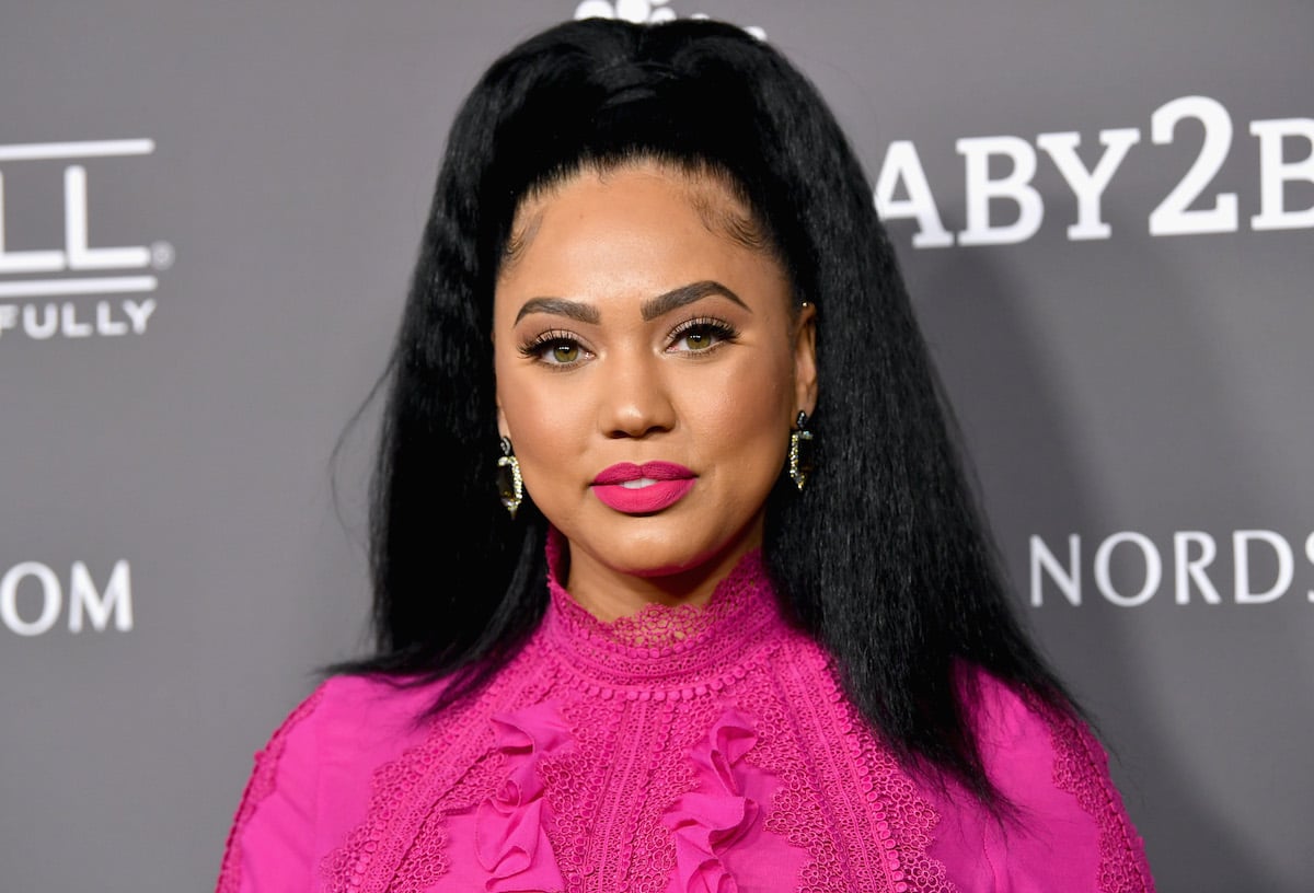 yesha Curry attends the 2018 Baby2Baby Gala wearing a pink top and a pink lip