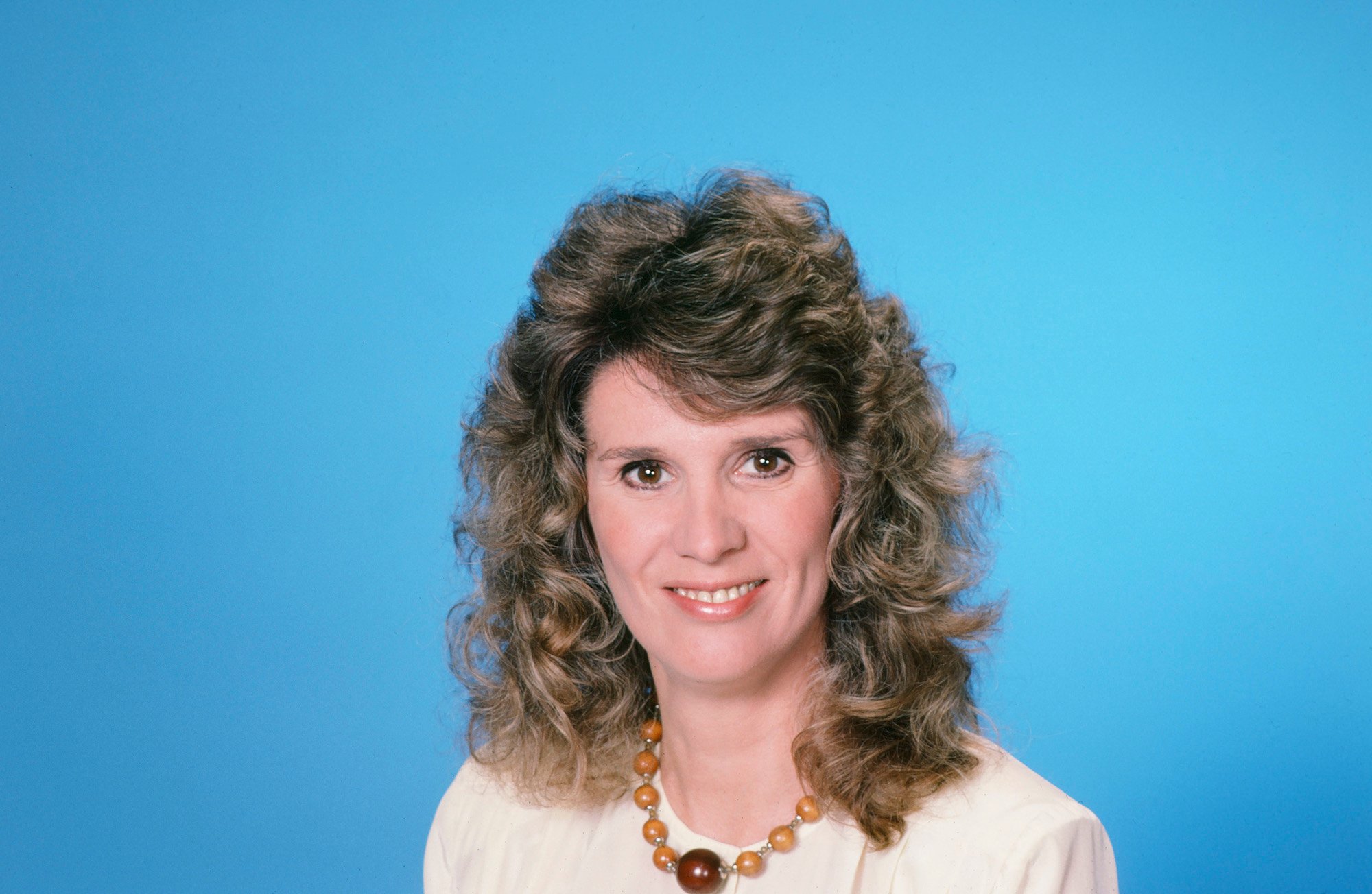 Barbara Bosson as Fay Furillo smiling in front of a bright blue background