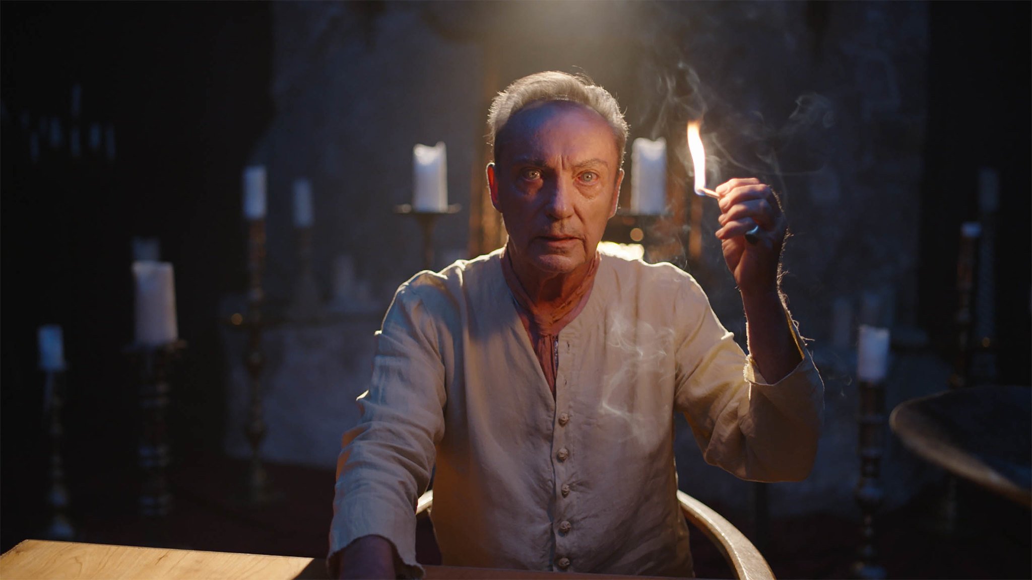 Blazing World star Udo Kier as Lanied with a lit match