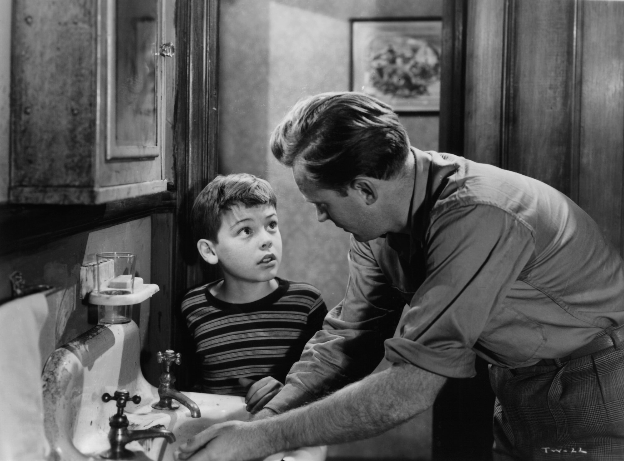 Bobby Driscoll looking up at Arthur Kennedy in a scene from the film 'The Window' in black and white