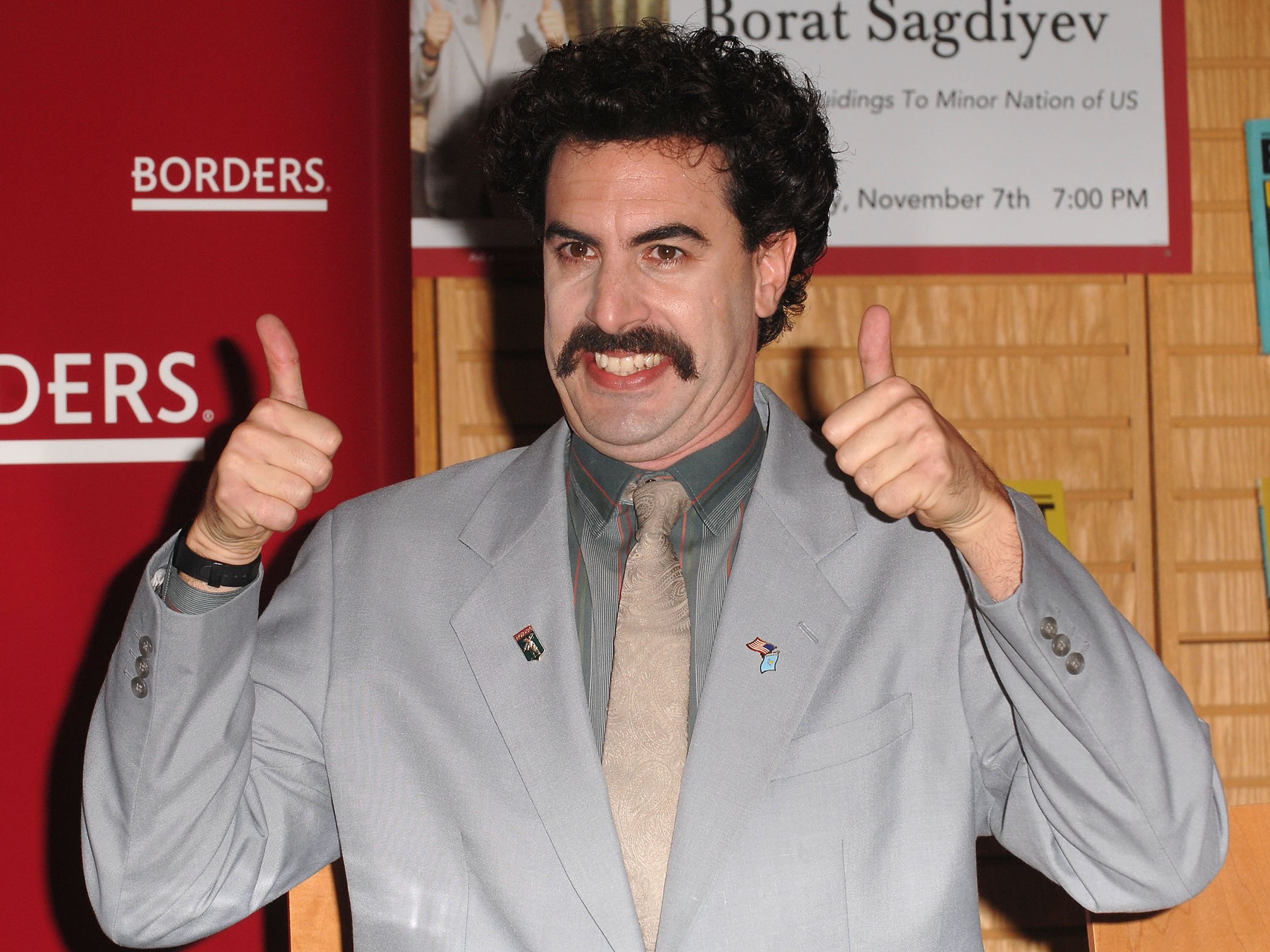Sacha Baron Cohen dressed as 'Borat' with two thumbs up 