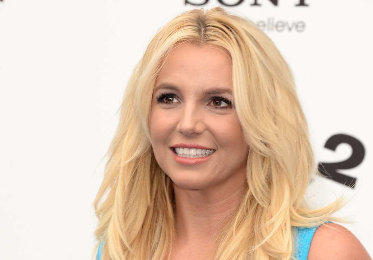 Britney Spears smiling while looking to the left wearing a turquoise top.