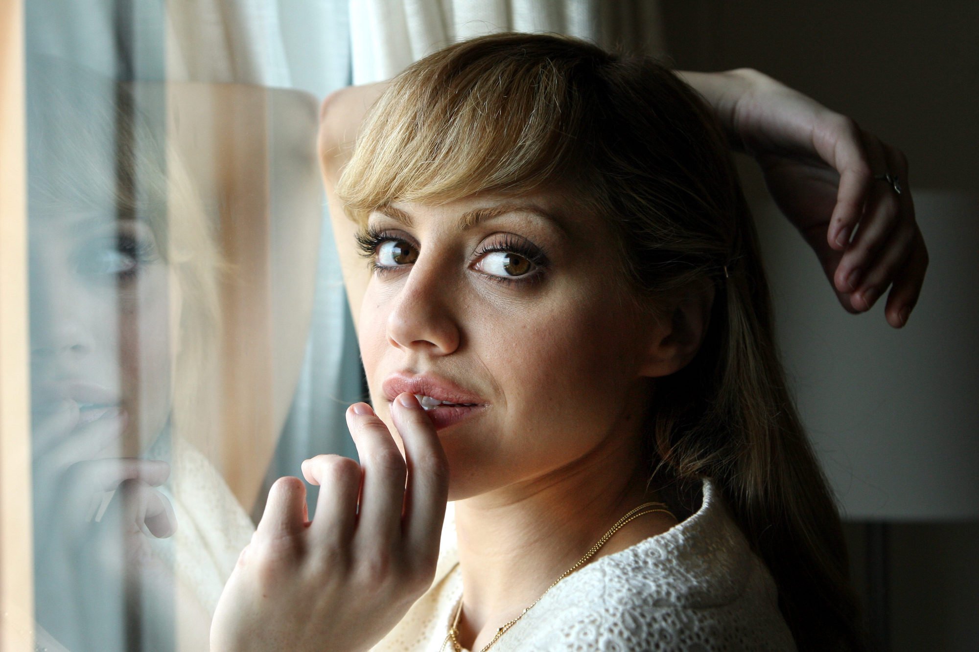 Brittany Murphy looking at the camera, with a hand resting against her mouth