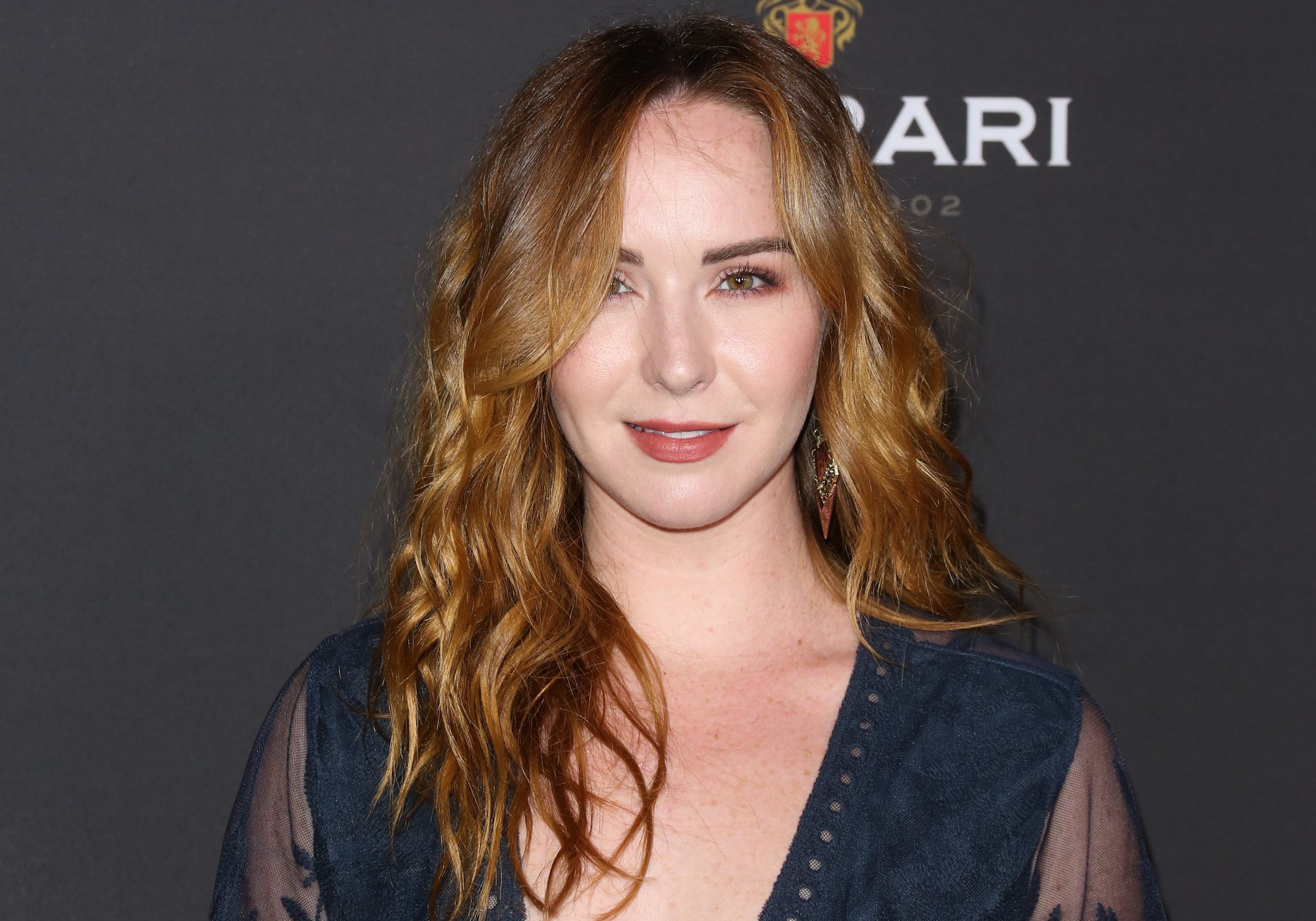 Camryn Grimes smiling in front of a gray background