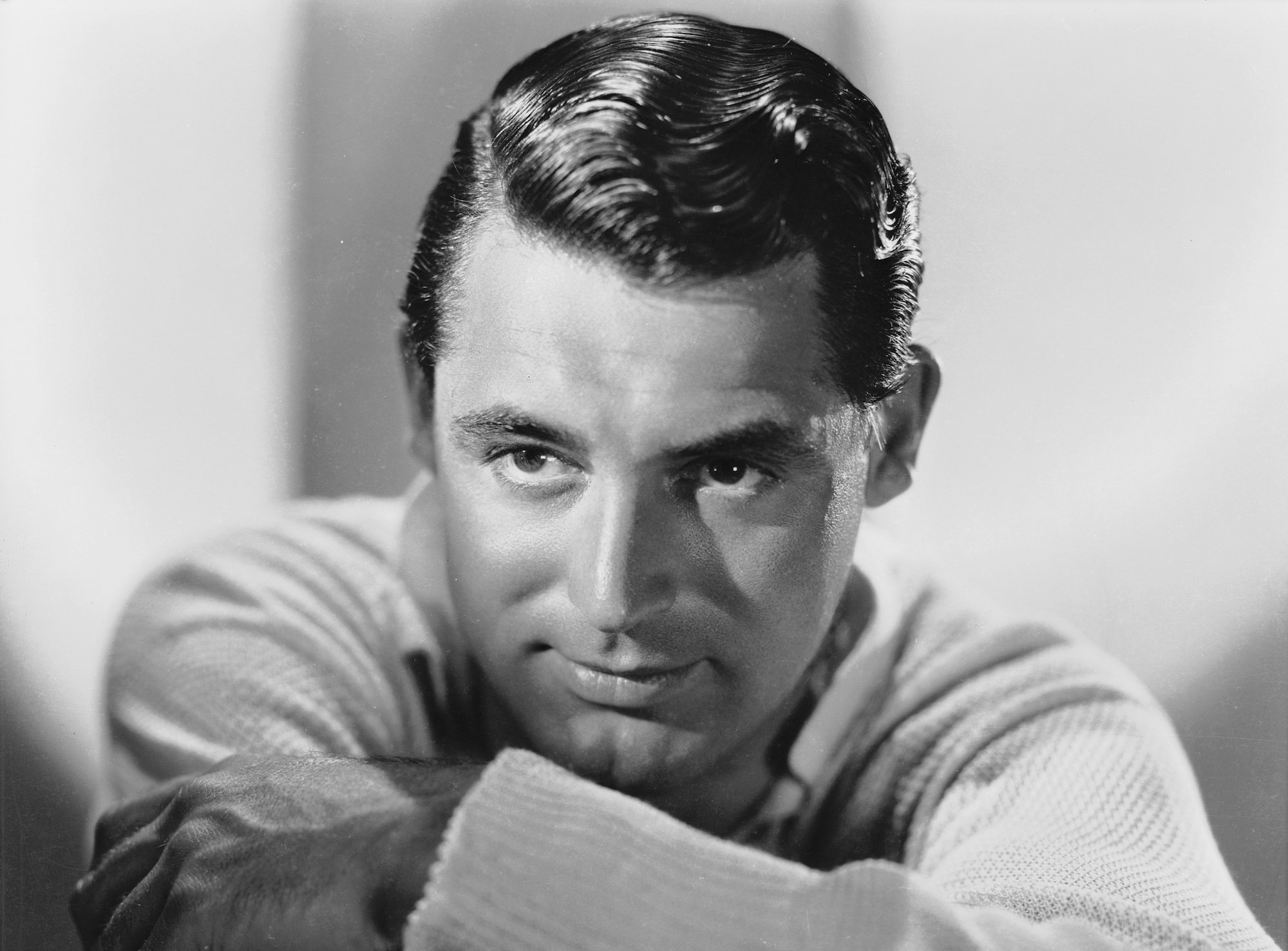 Cary Grant leaning on his folded hands, looking to the left, in black and white