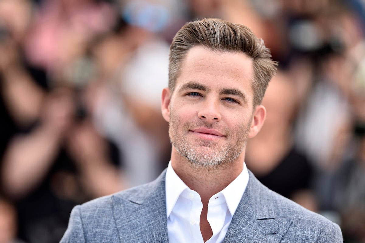 Chris Pine headshot at a red carpet event outdoors. He is wearing a gray suit.