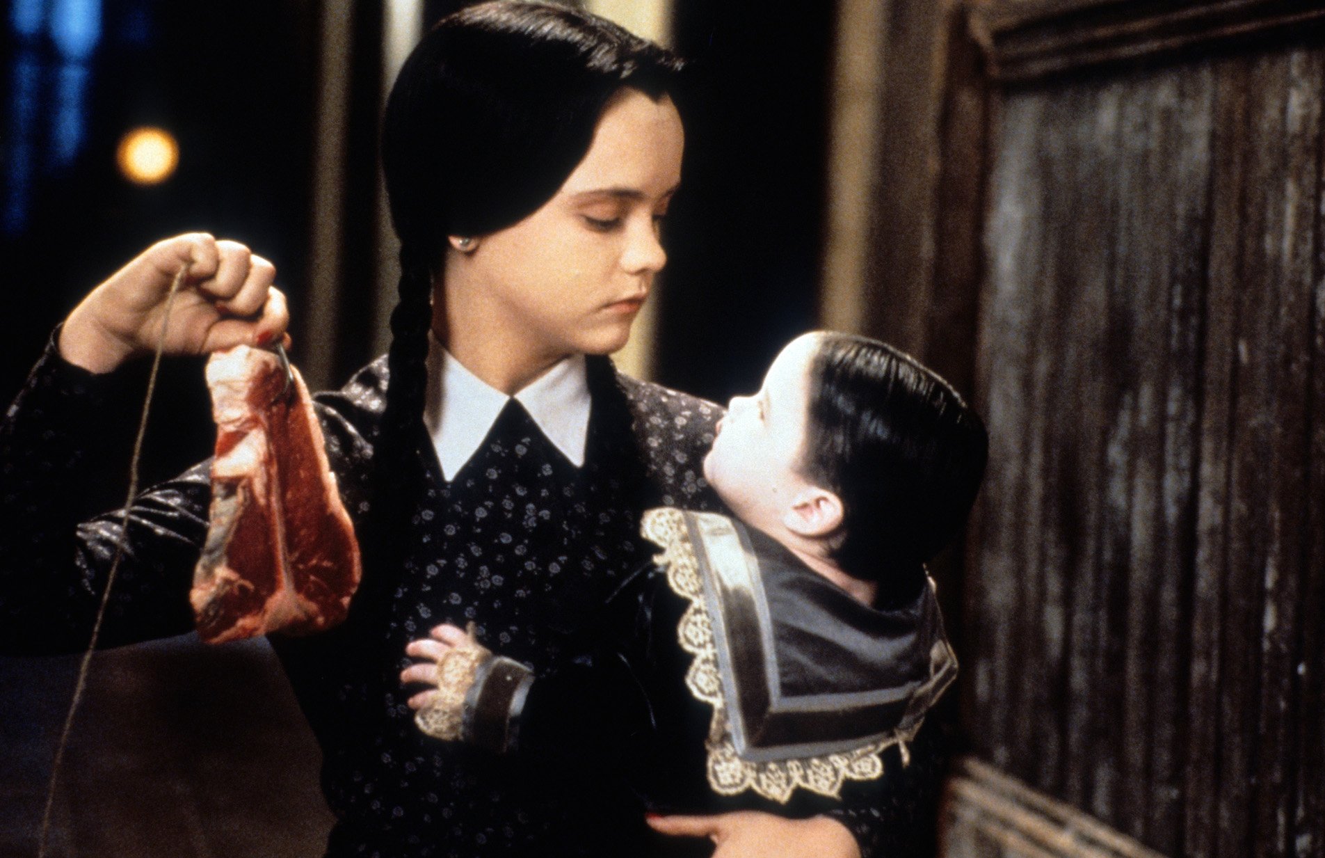 Christina Ricci as Wednesday Addams dangling meat in front of a baby in 'Addams Family Values'
