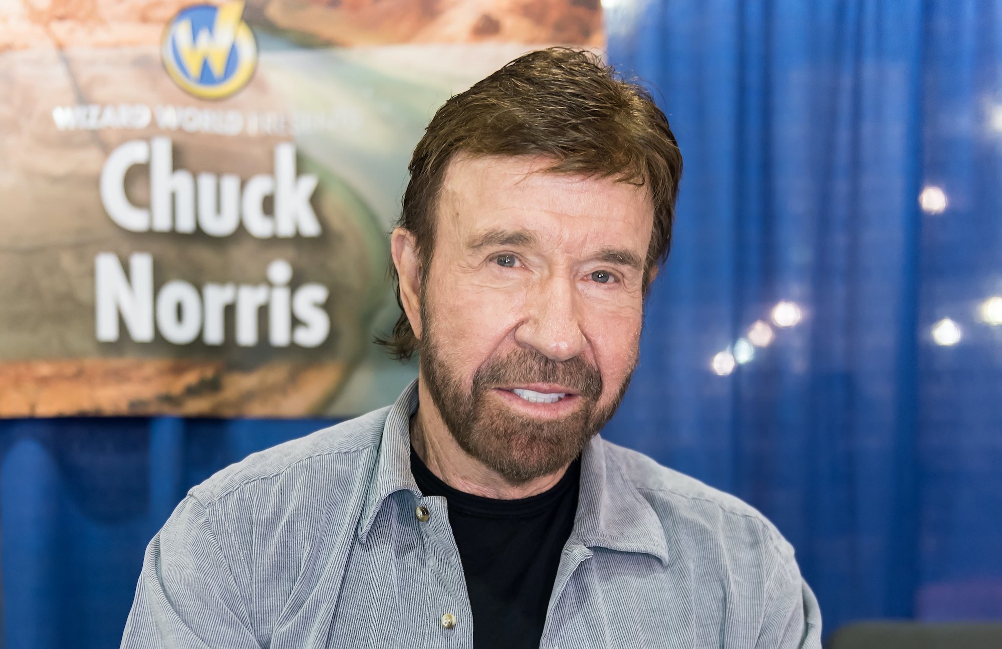 Chuck Norris smiling in front of a blue background