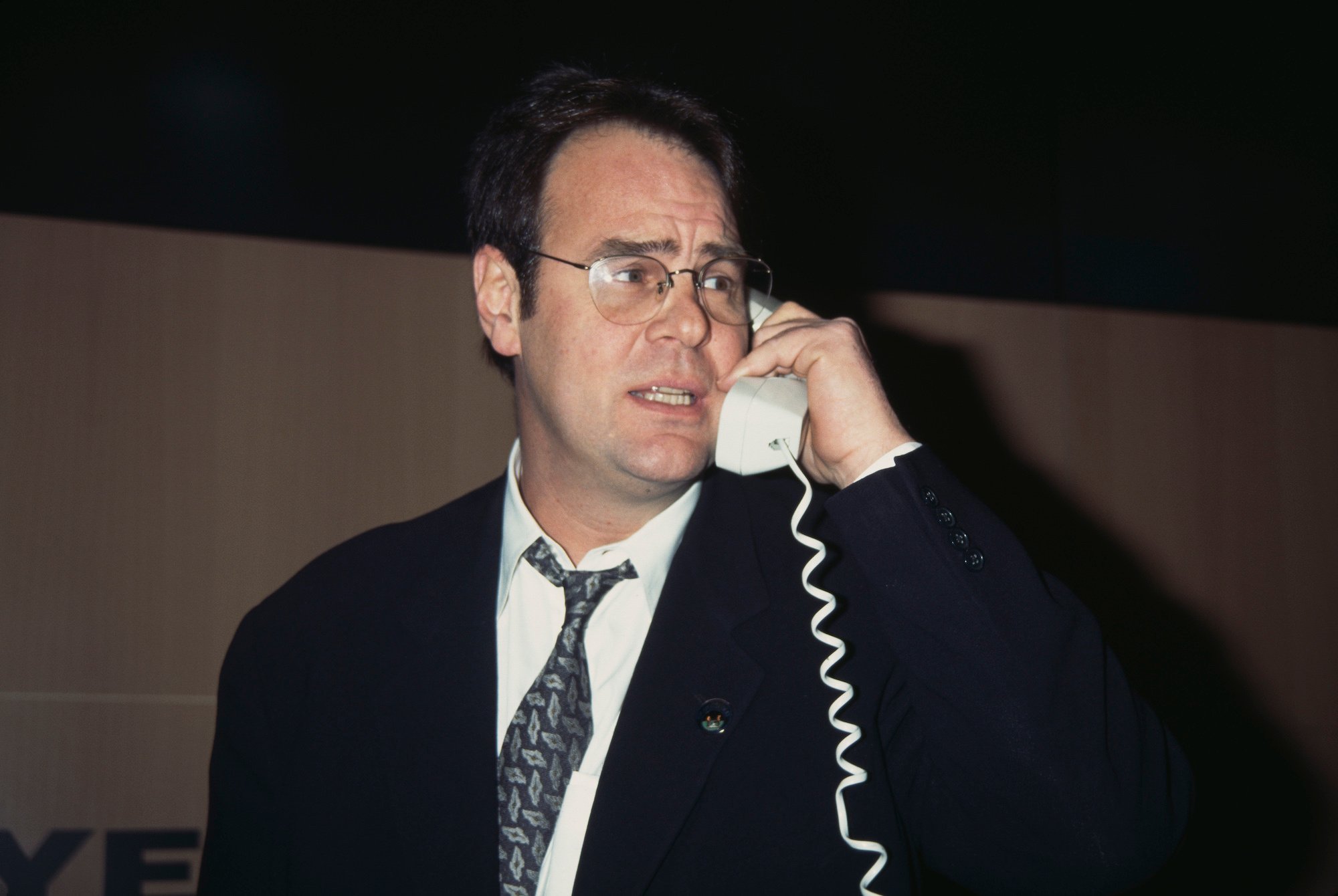 Dan Aykroyd turned to the side, on a corded phone