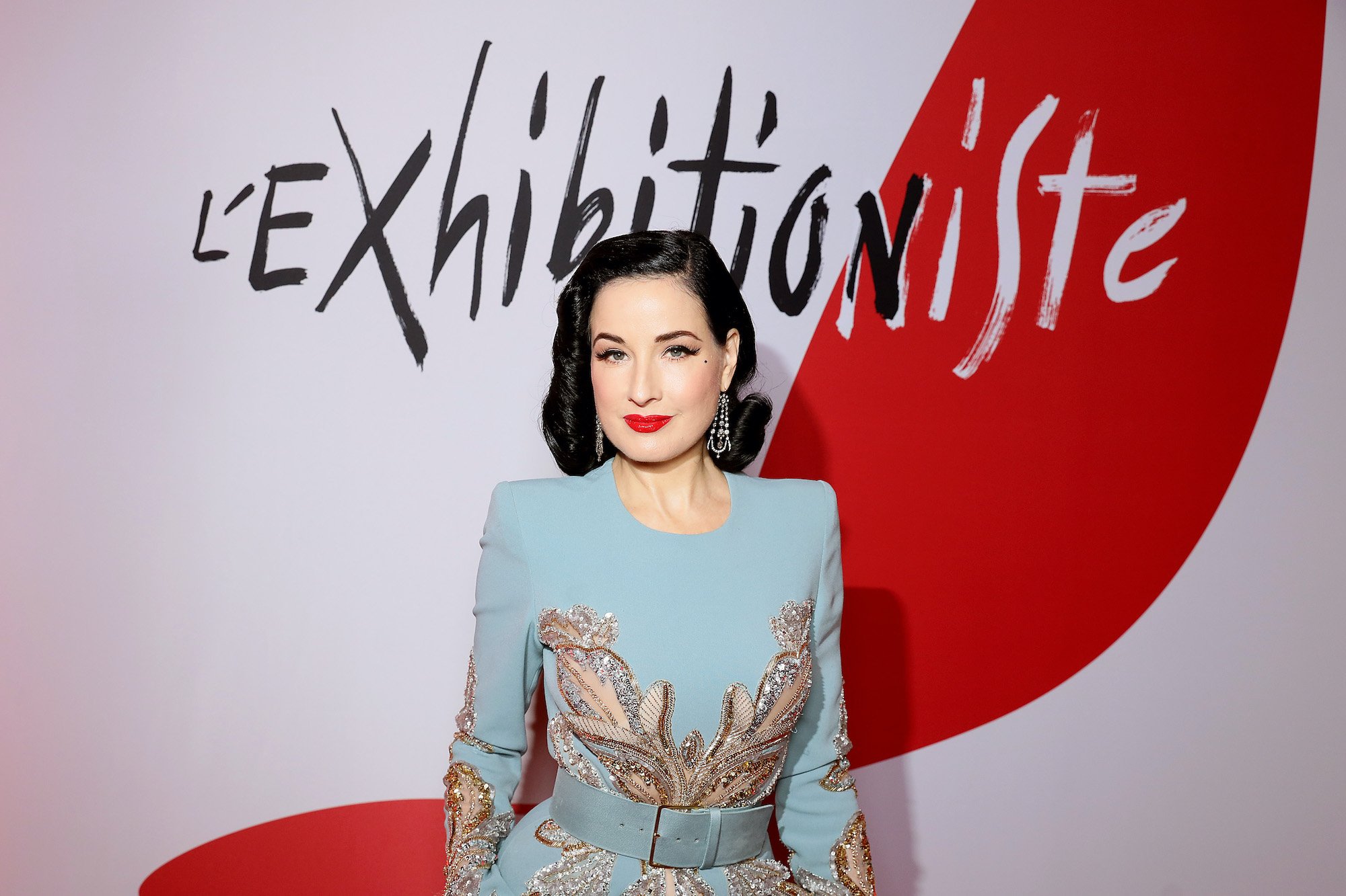 Dita Von Teese in front of a red and white background
