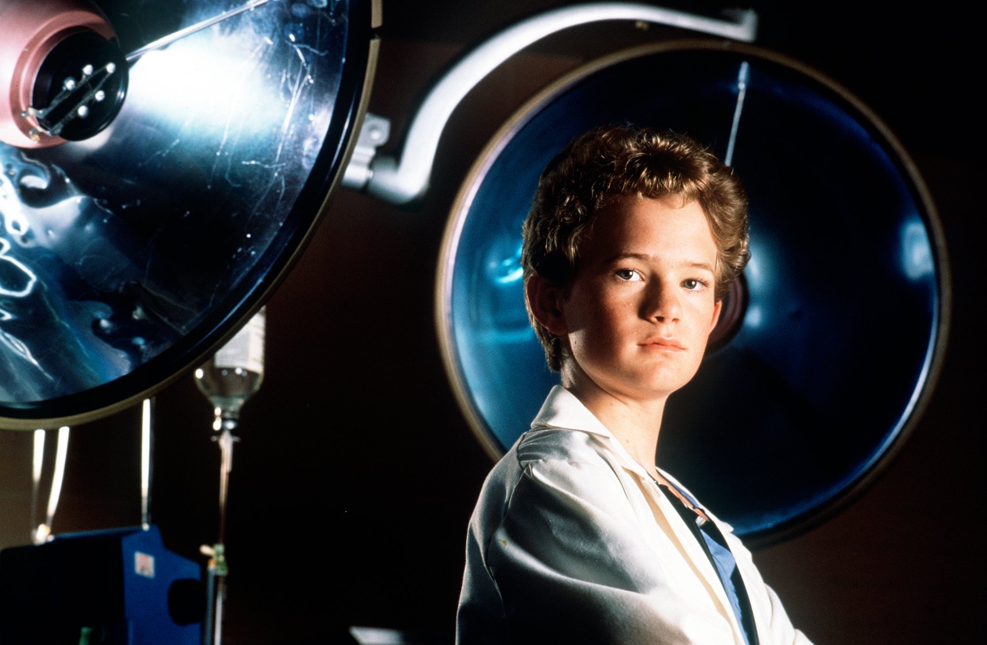 Neil Patrick Harris as Douglas "Doogie" Howser standing in front of medical equipment