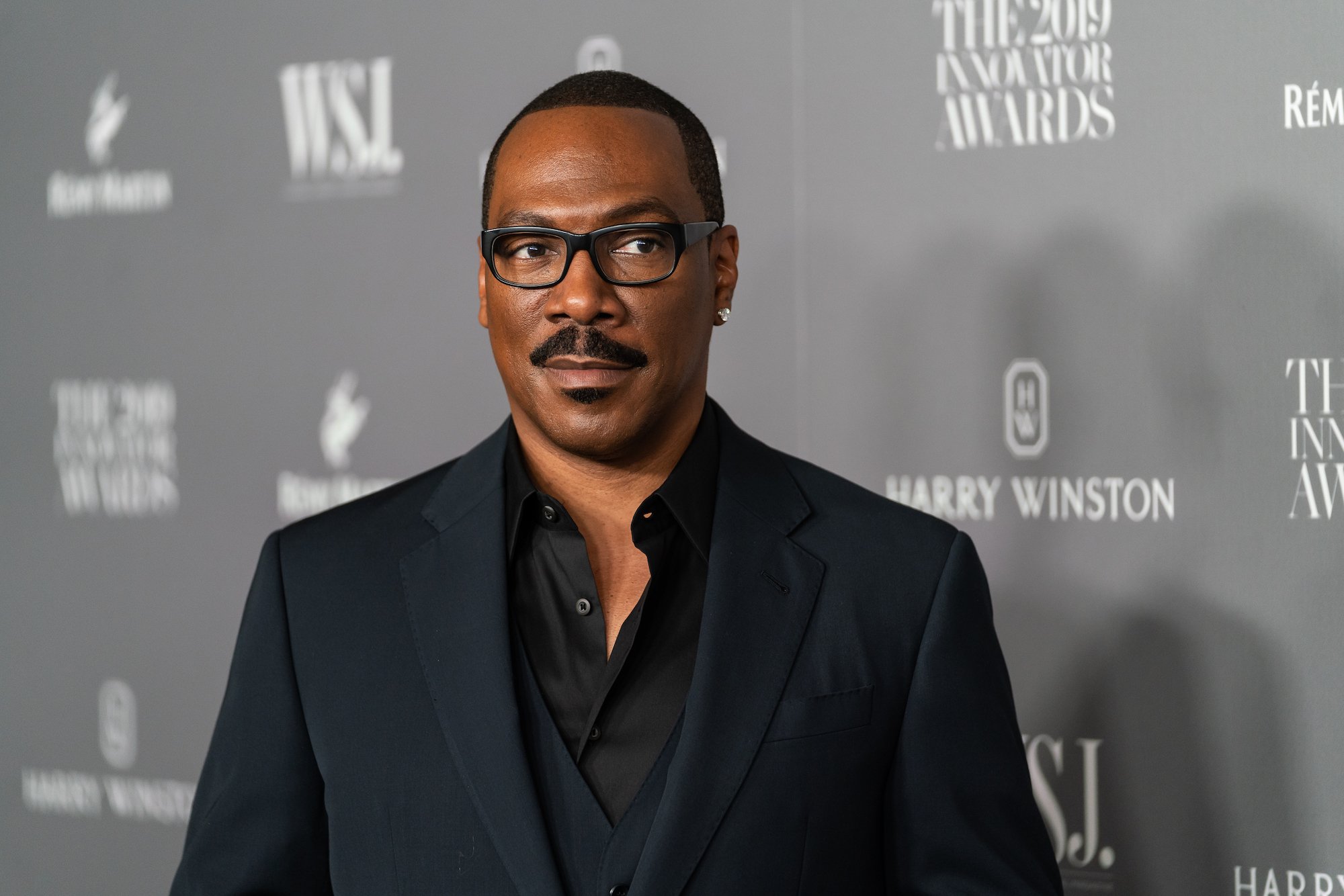 Eddie Murphy smiling in front of a gray background