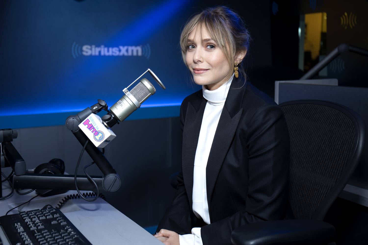 Elizabeth Olsen in a white turtleneck and a black blazer