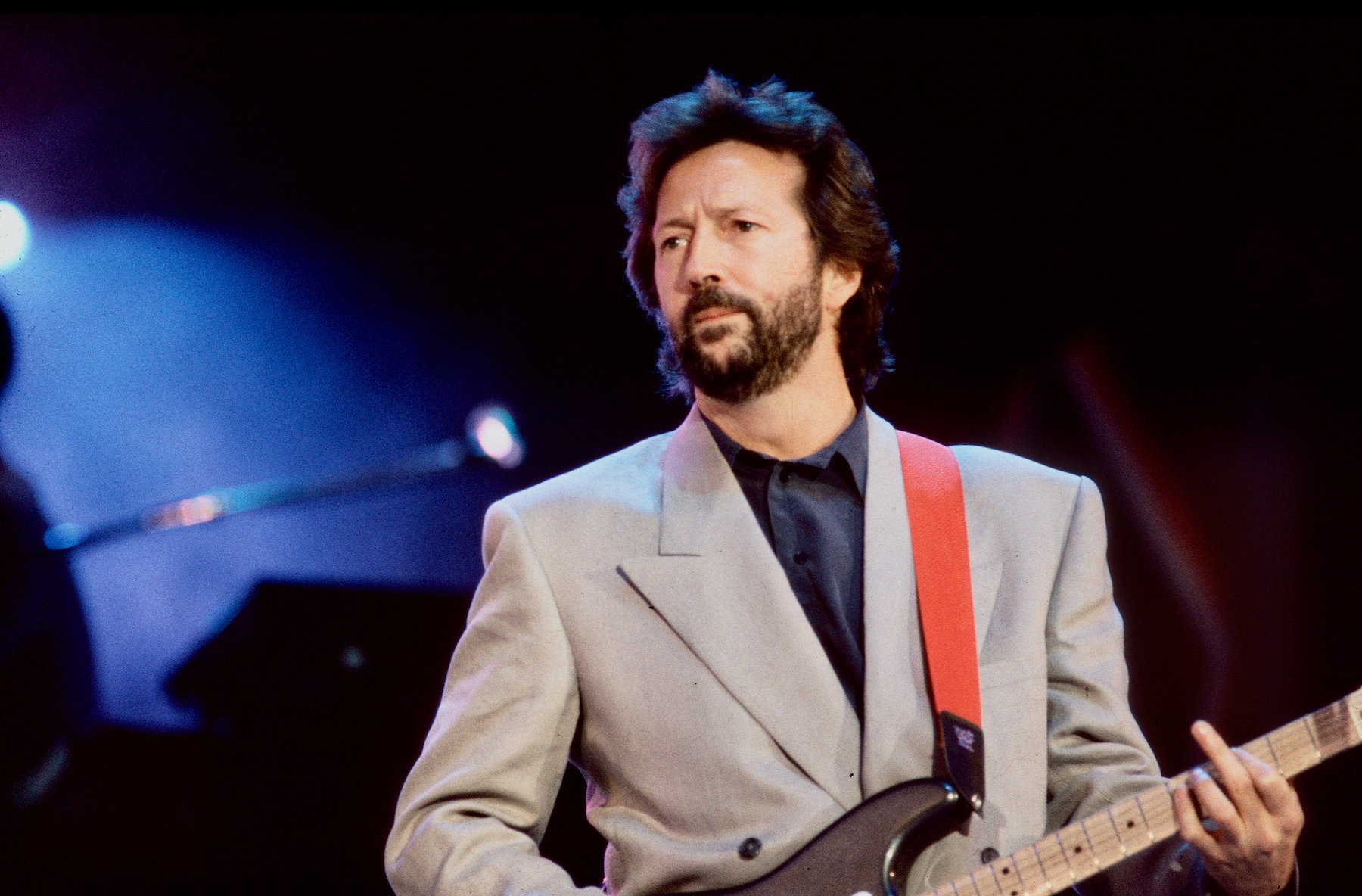 Eric Clapton on stage with a guitar in front of a dark background