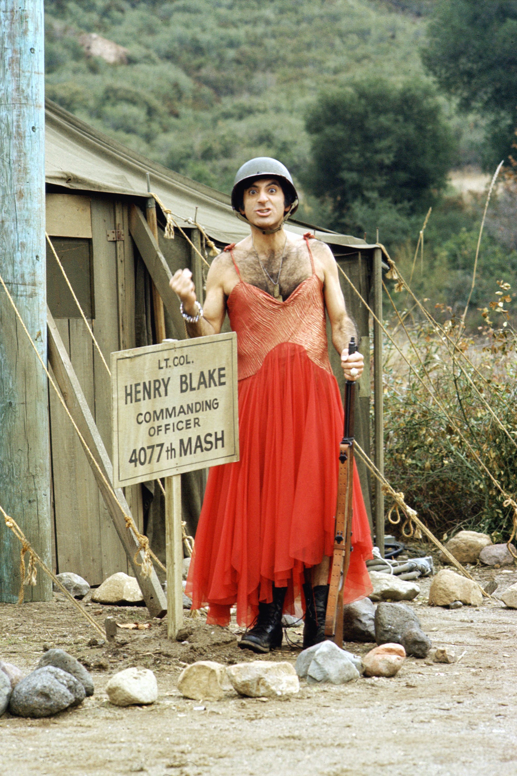 Jamie Farr in red dress and combat helmet as Max Klinger on 'M*A*S*H', 1974