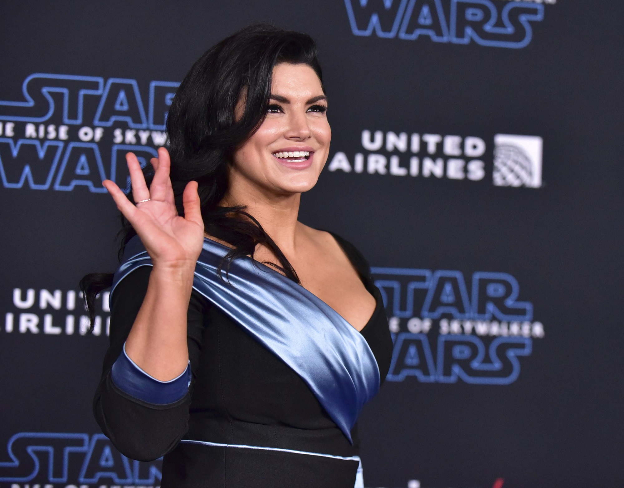 Gina Carano waves at the camera while attending the premiere of 'Star Wars: The Rise of Skywalker'