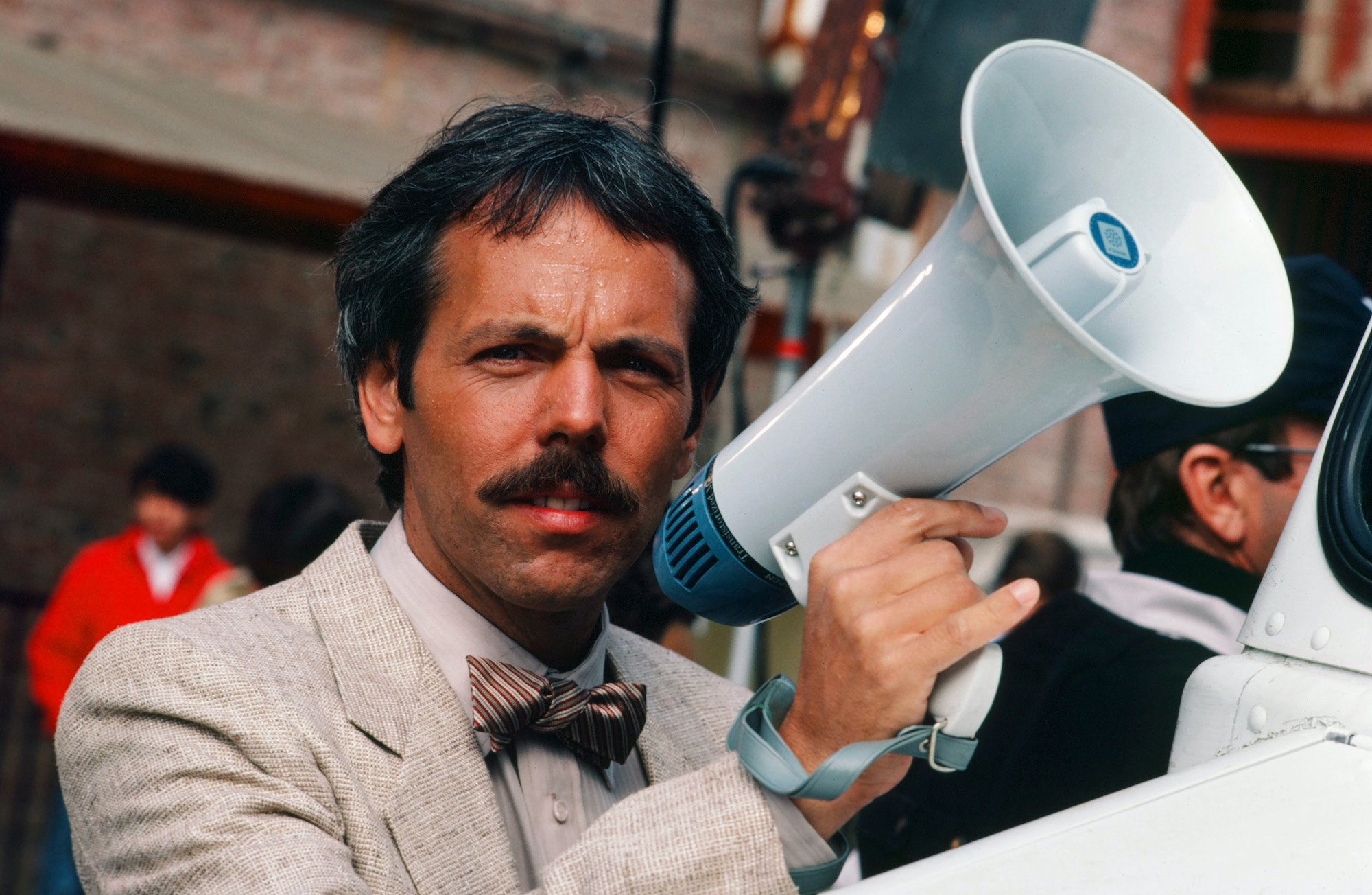 Joe Spano as Sgt./Lt. Henry Goldblum holding a megaphone, squinting, wearing a jacket and bow tie
