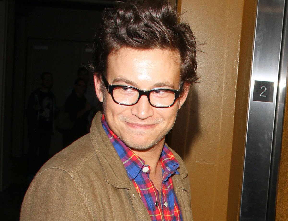 Jonathan Taylor Thomas in a blue and red checkered shirt, a tan coat, and black-rimmed glasses while out on August 14, 2013 in Los Angeles, California | GT/Star Max/FilmMagic