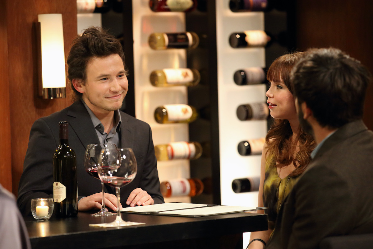 Jonathan Taylor Thomas in a grey suit with a glass of wine in front of him in a special guest star appearance on Tim Allen's 'Last Man Standing' | Craig Sjodin/Walt Disney Television via Getty Images