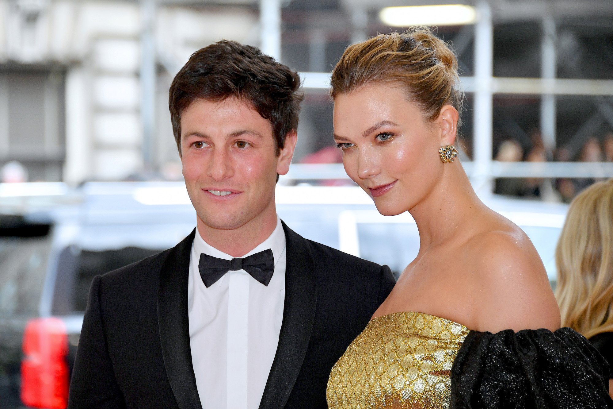(L-R) Joshua Kushner and Karlie Kloss smiling in front of a blurred background