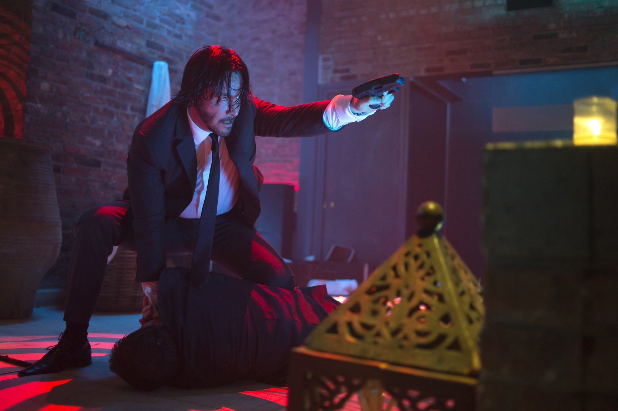 John Wick crouched and pointing a gun