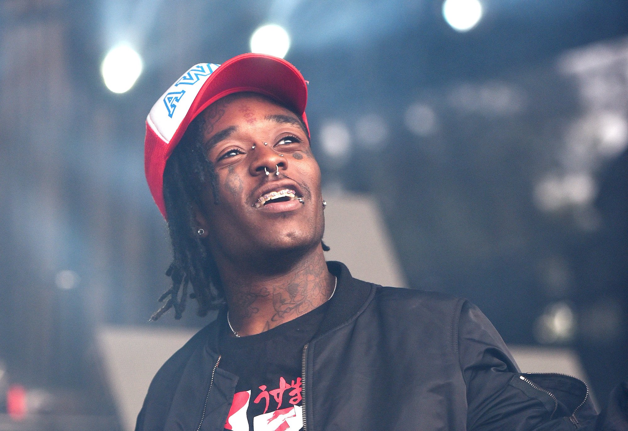 Lil Uzi Vert smiling, looking up, in front of a blurred stage