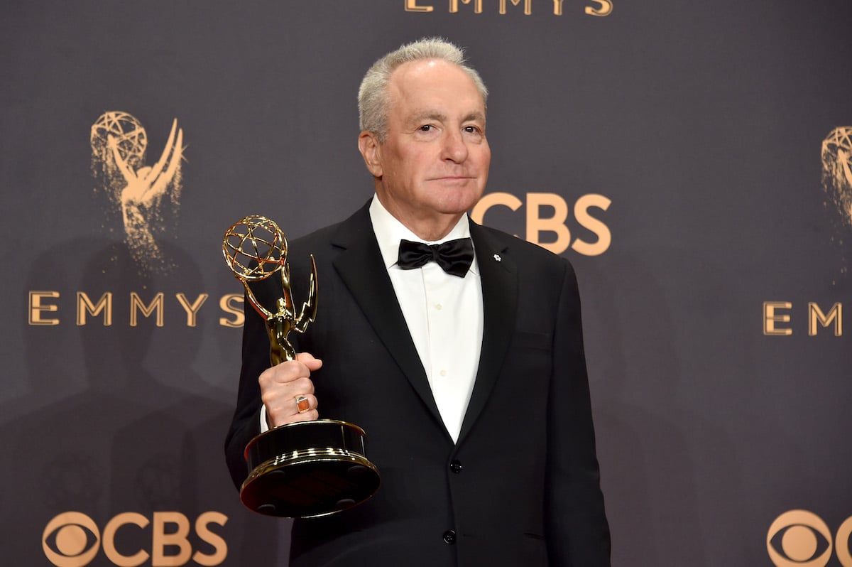 Lorne Michaels poses in a formal suit holding an award in his right hand.