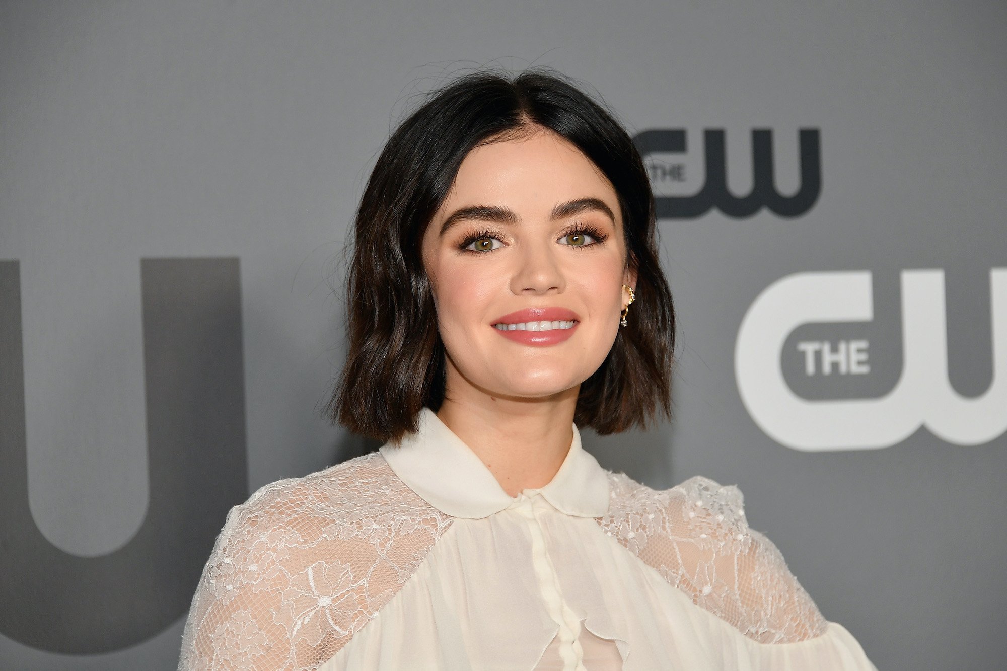 Lucy Hale smiling in front of a gray background