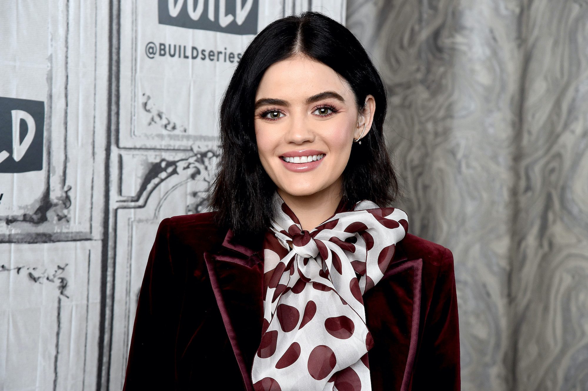 Lucy Hale smiling in front of a gray background