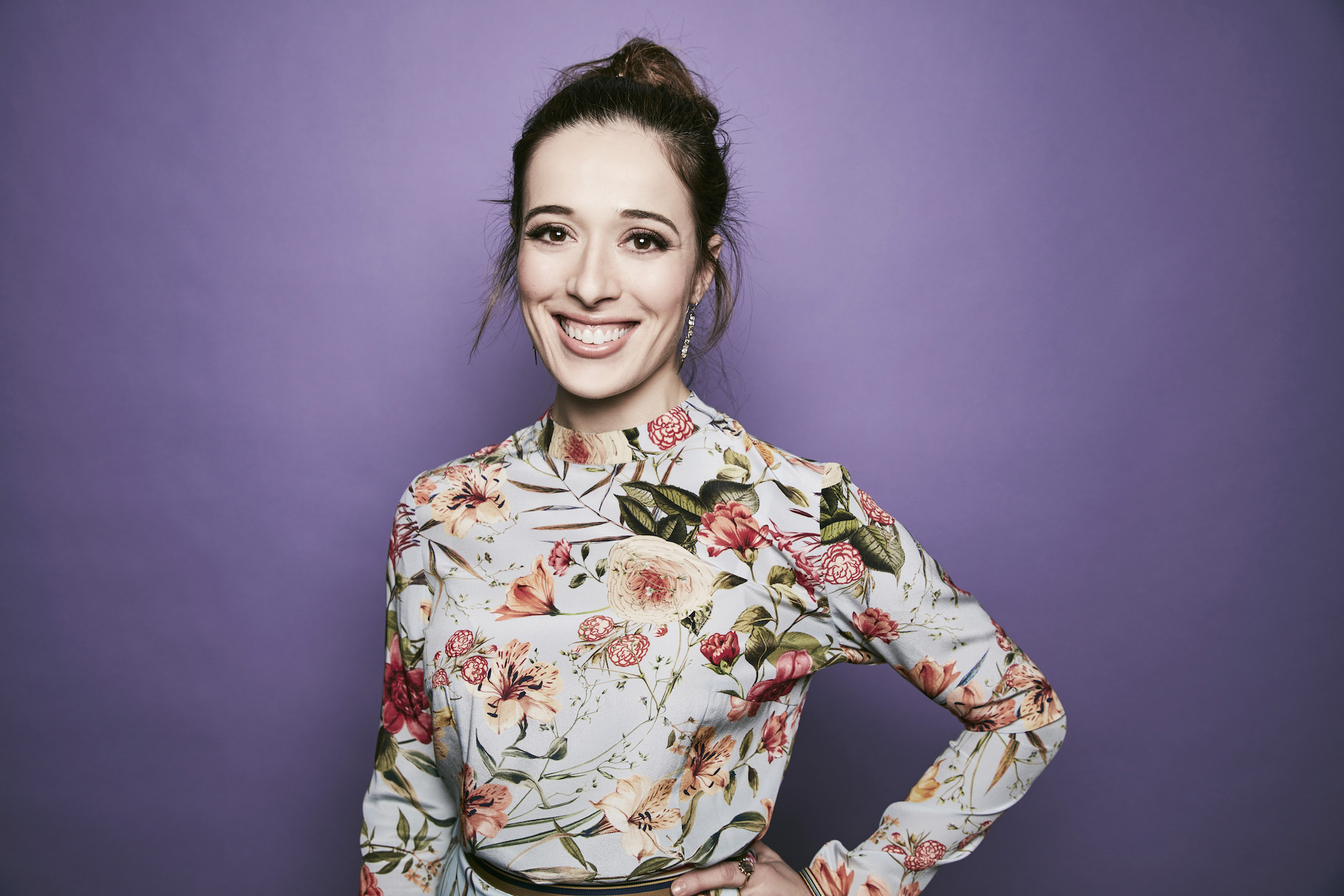 Marina Squerciati smiling in front of a purple background
