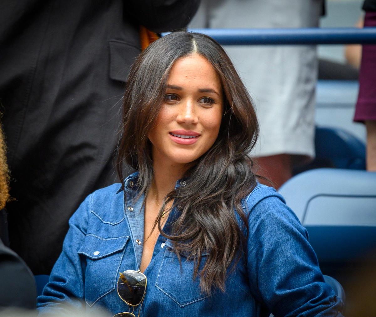 Meghan Markle wearing a blue shirt in the audience of sports match