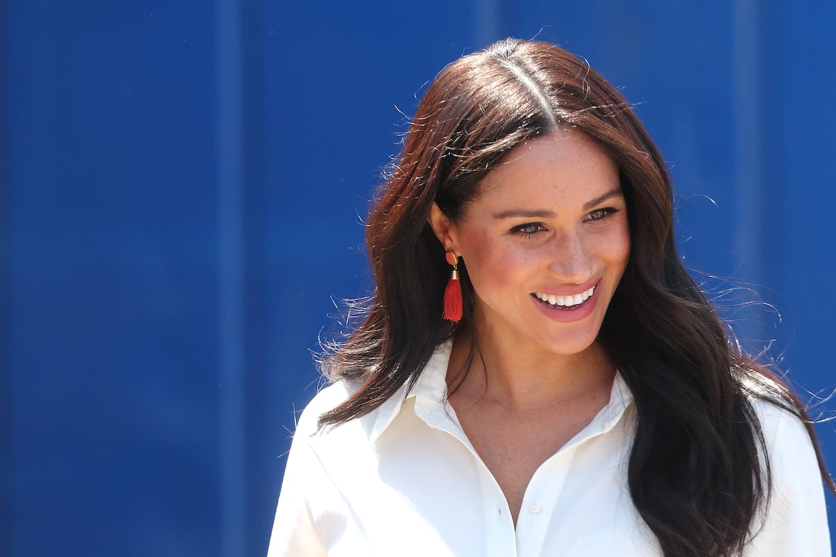 Meghan, Duchess of Sussex in South Africa smiling wearing a white shirt