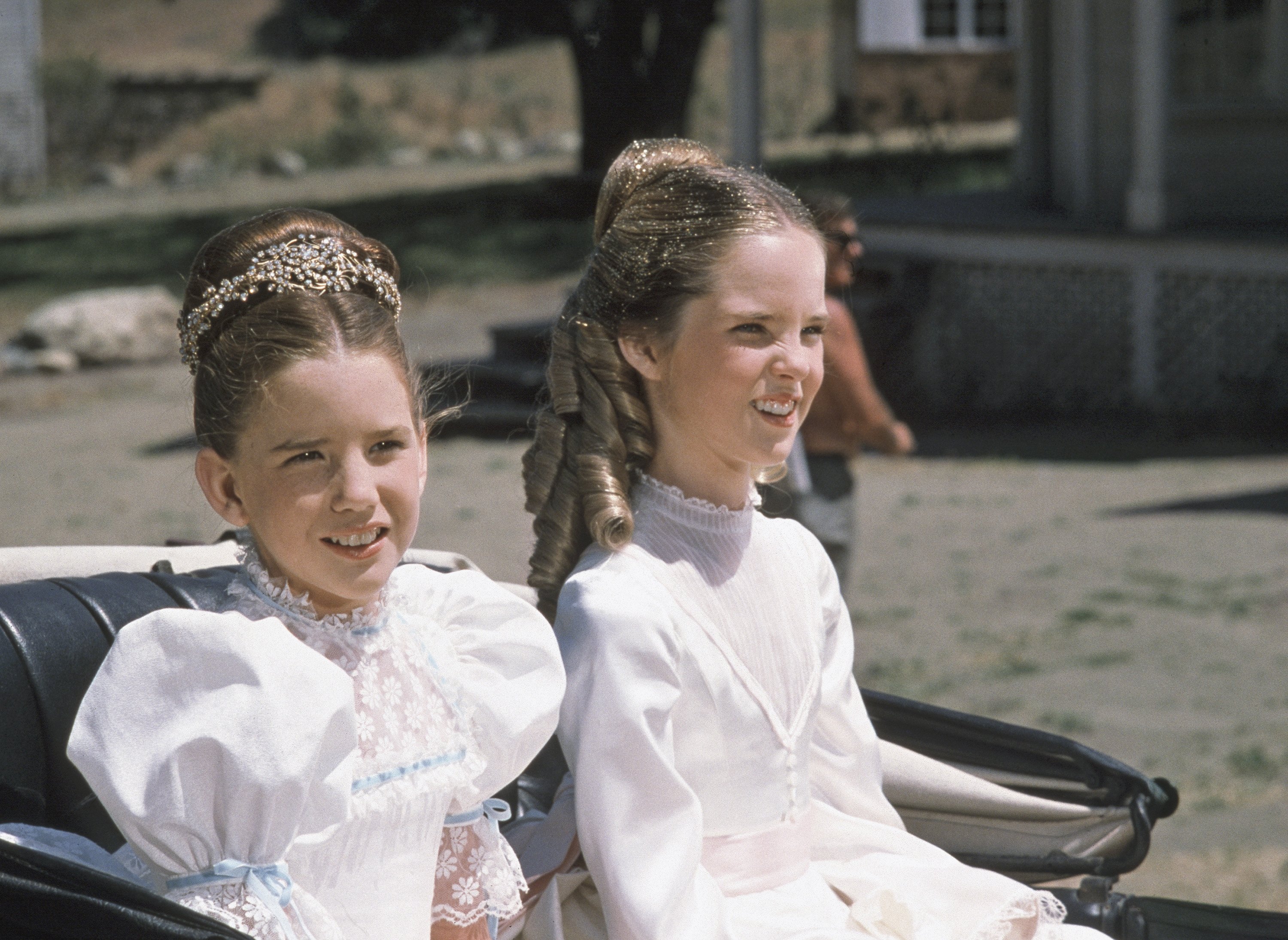 Melissa Gilbert and Melissa Sue Anderson on set at 'Little House on the Prairie.' The TV sisters are dressed in white dresses sitting in a carriage.