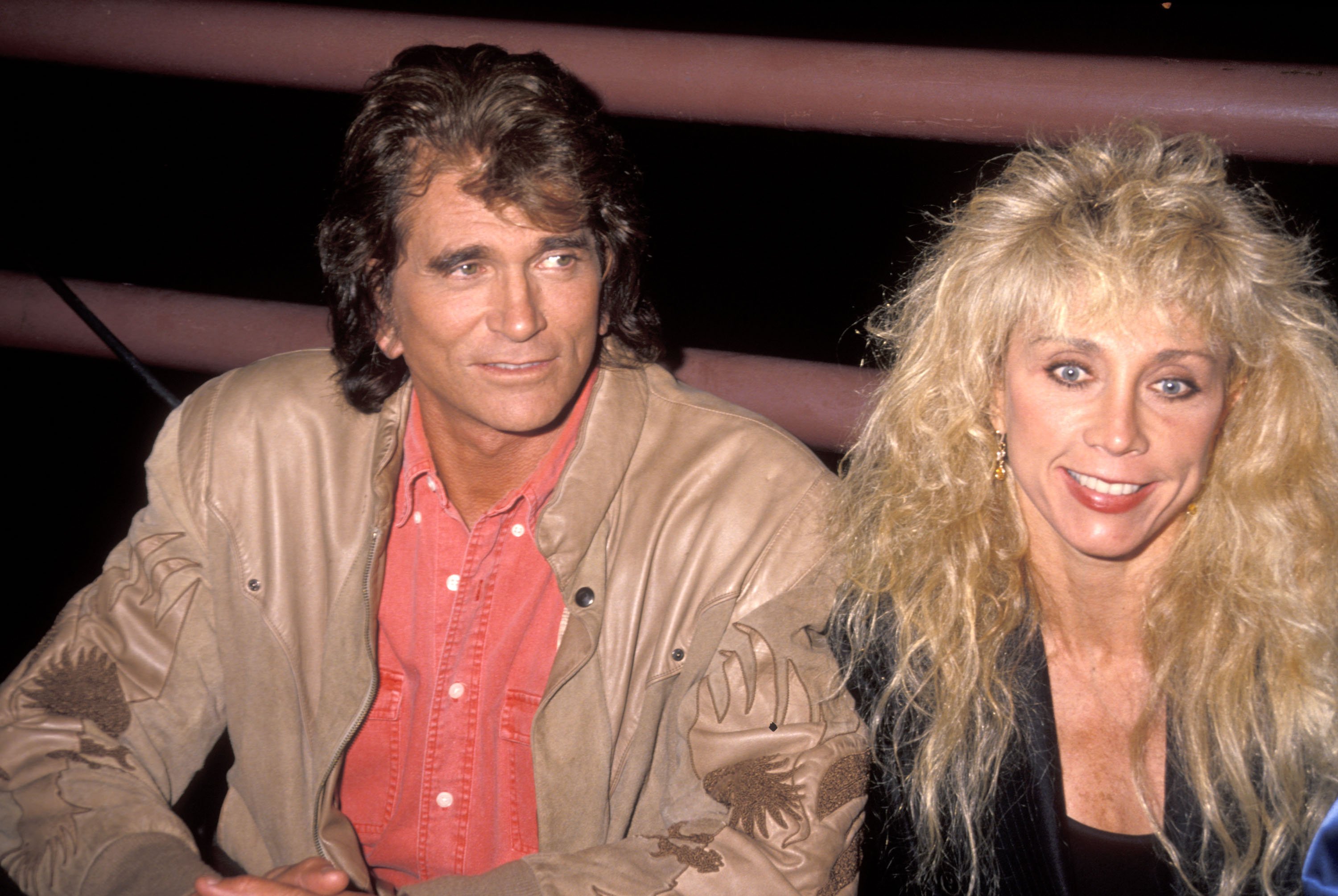Michael Landon in a red shirt smiling and Cindy Landon smiling in a black jacket.