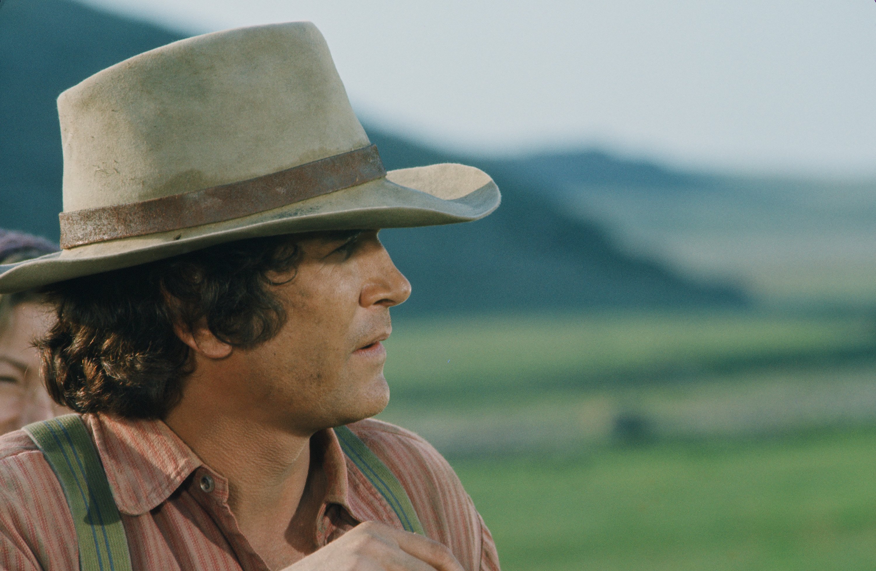 Michael Landon with a tan and brown hat and a red shirt.