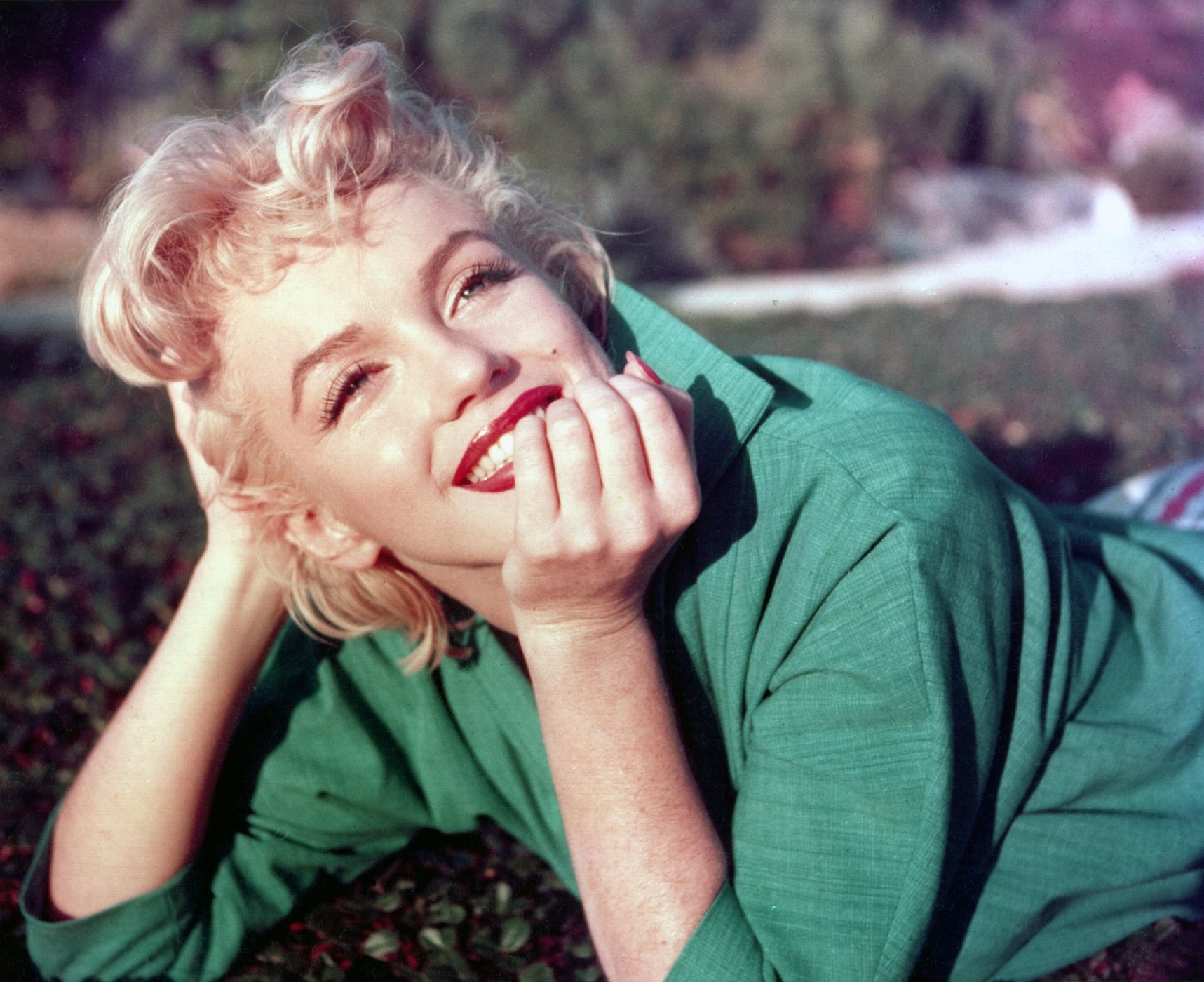  Marilyn Monroe poses for a portrait laying on the grass in 1954 in Palm Springs, California
