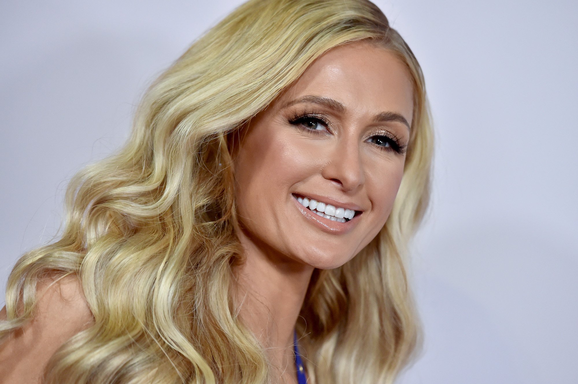 Paris Hilton smiling in front of a white background