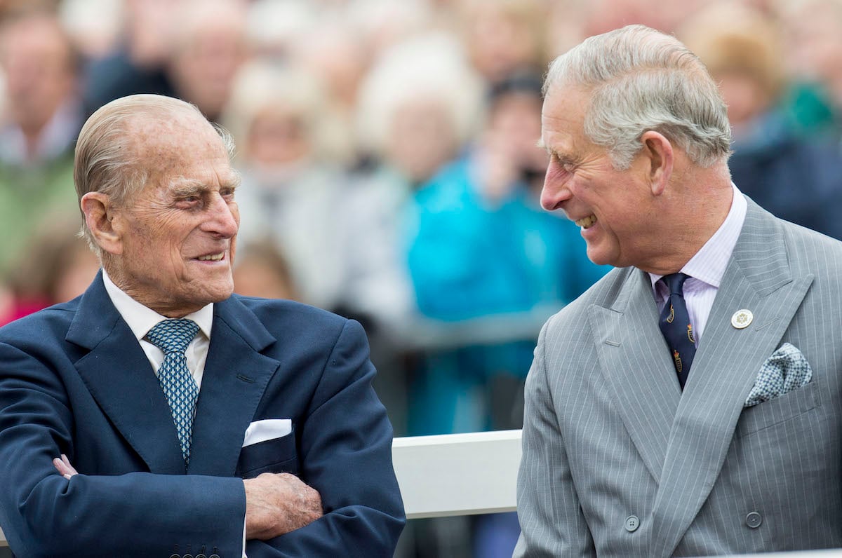 Prince Philip, and Prince Charles smiling at each other
