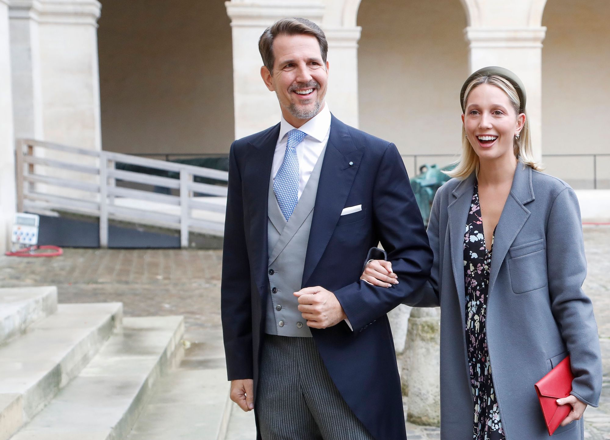 (L-R) Crown Prince Pavlos of Greece and Crown Princess Marie-Chantal smiling, holding hands, standing on a set of steps