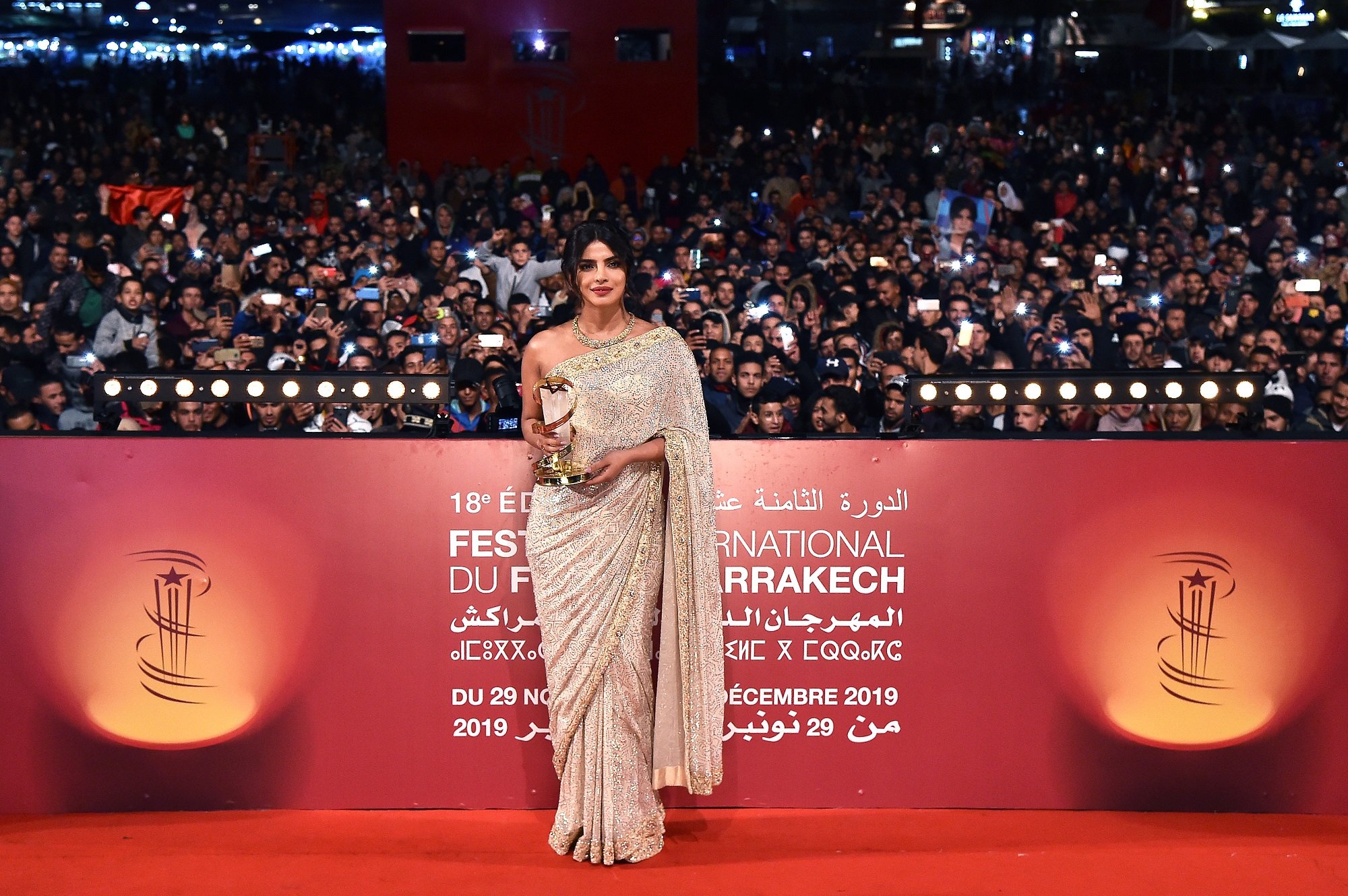Priyanka Chopra Jonas on a red carpet with a trophy