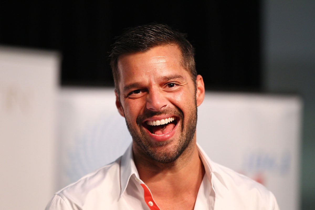 Ricky Martin headshot with the singer smiling at the camera with his mouth open.