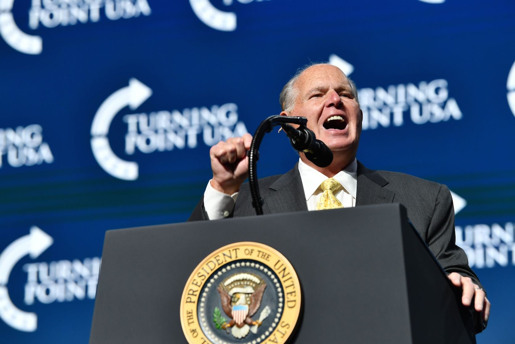 Rush Limbaugh shouting into a microphone at a summit