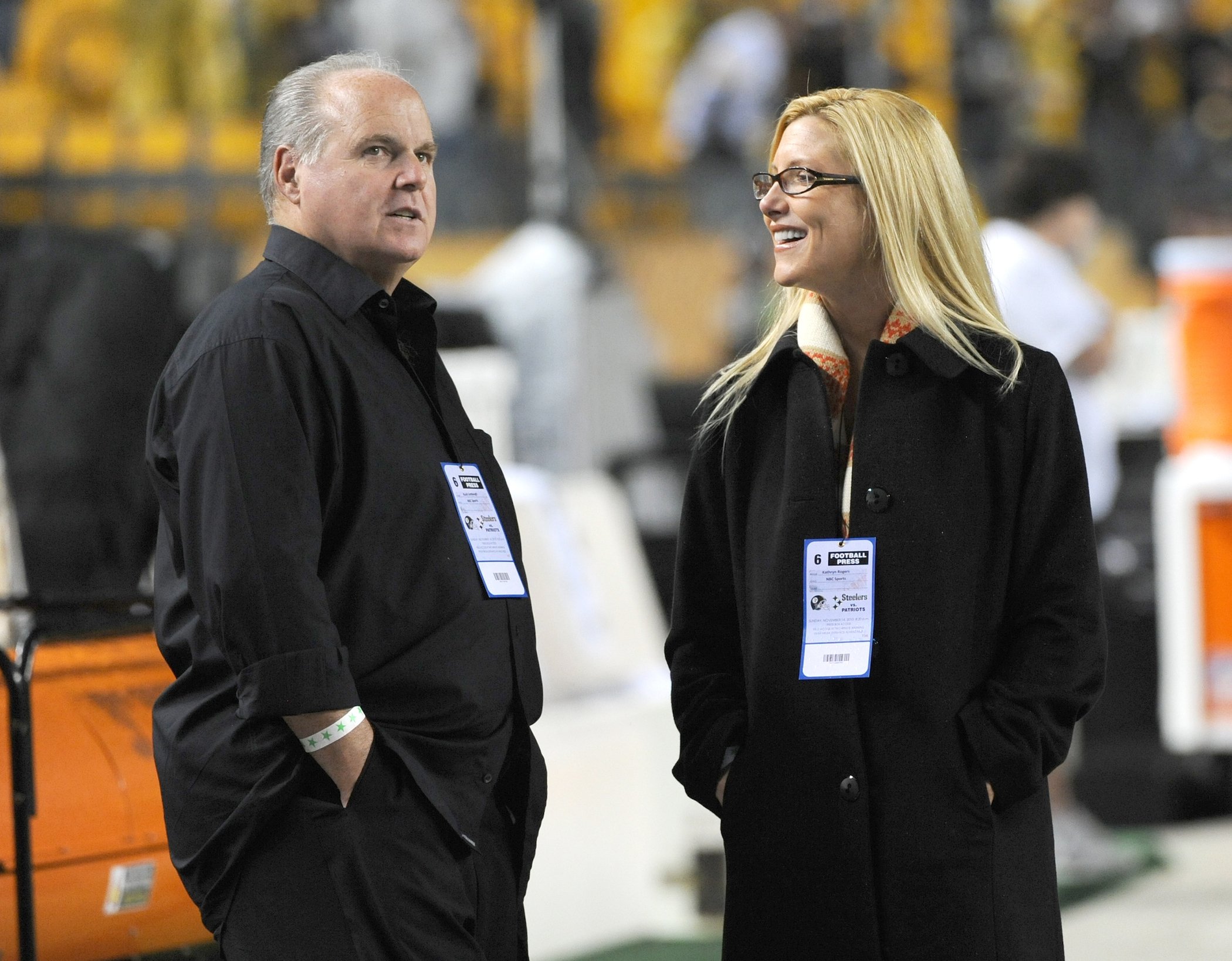 Rush Limbaugh (L) and his wife, Kathryn Adams Limbaugh, standing on the sidelines of a football game 