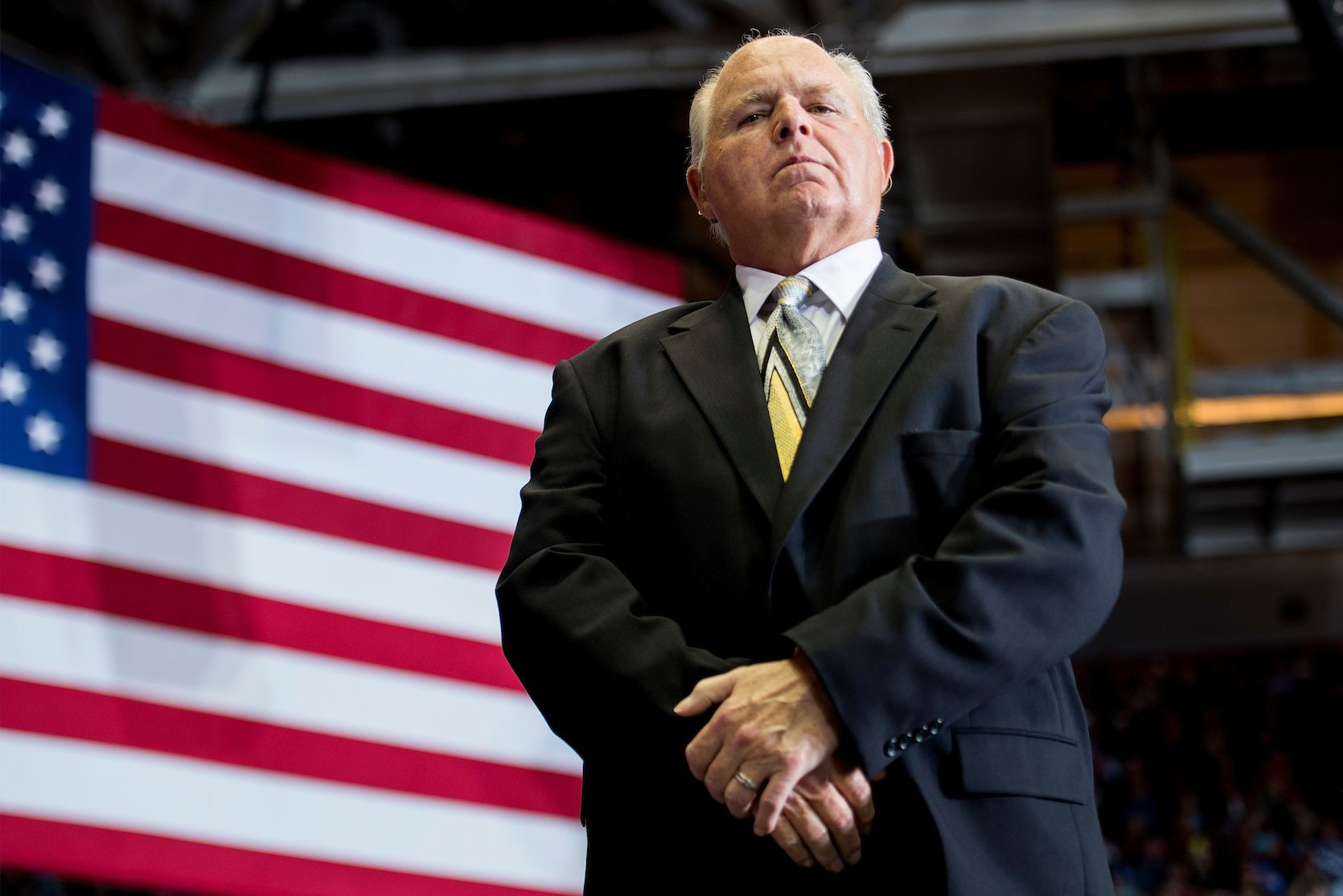 Rush Limbaugh standing in front of an American flag