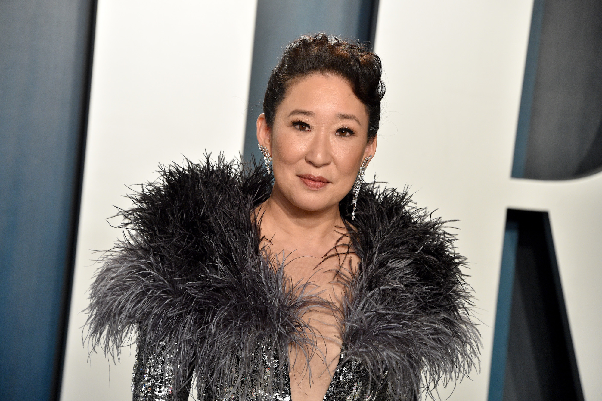 Sandra Oh smiling in front of a blue and white background